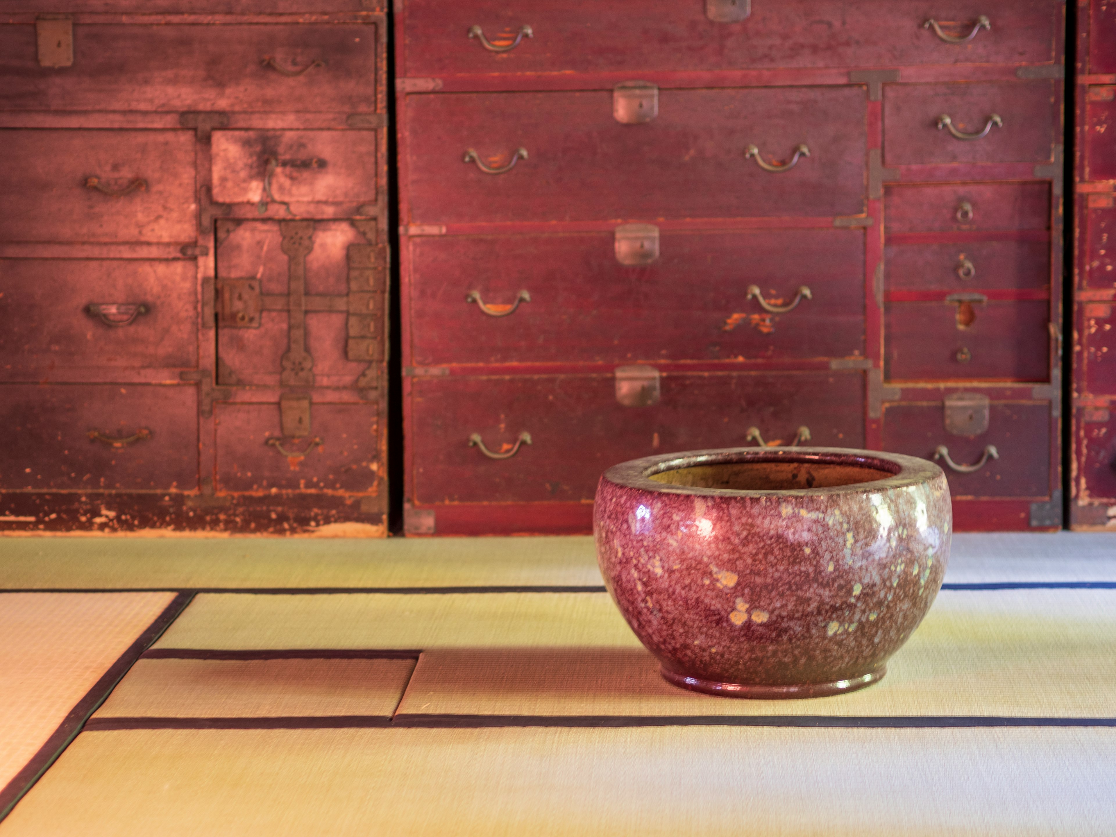 Ceramic bowl placed in front of a wall lined with antique wooden drawers