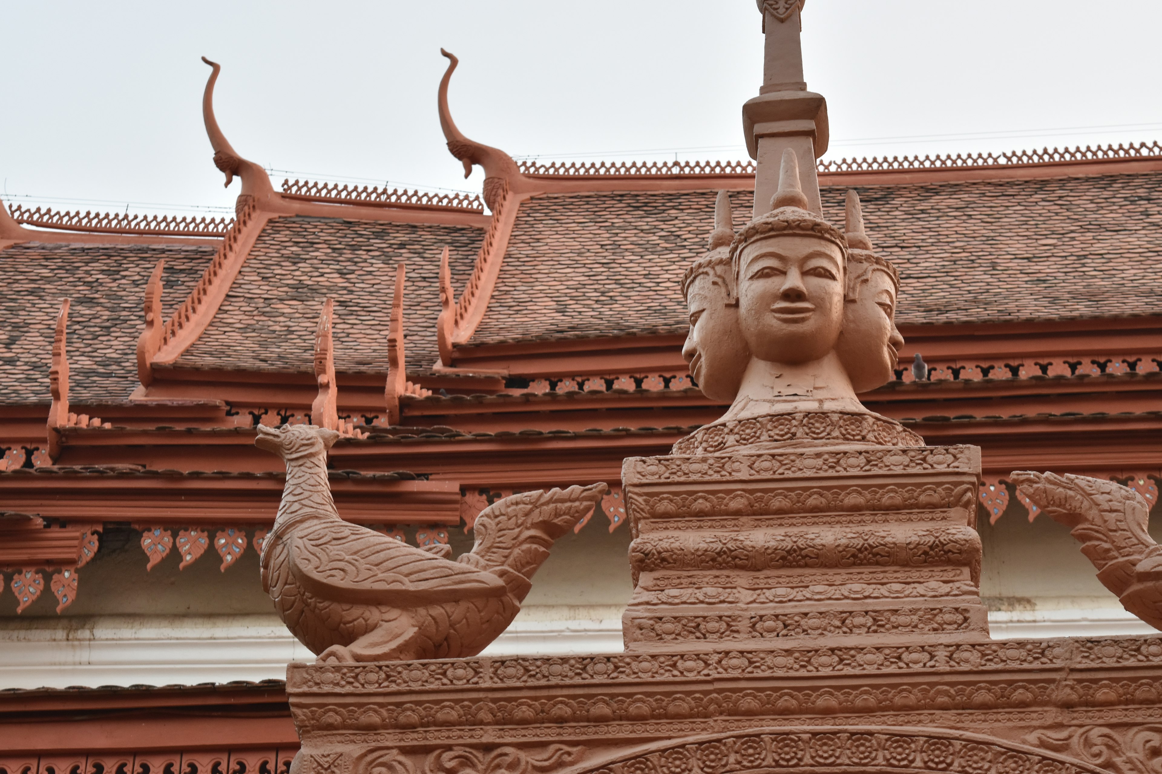 赤茶色の寺院の装飾的な彫刻である女性の顔と孔雀の像