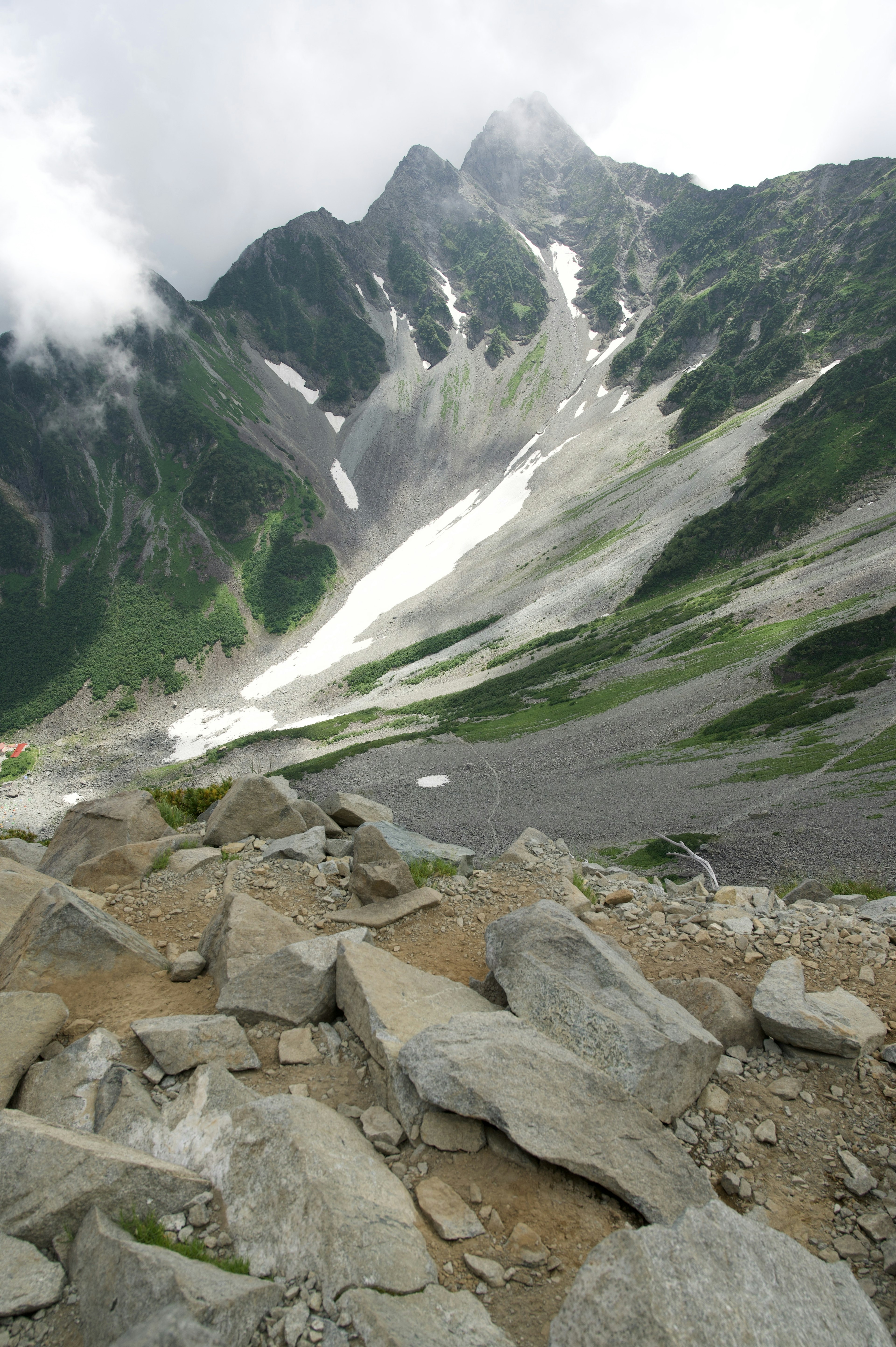 Pendio montano con terreno roccioso e cime nuvolose