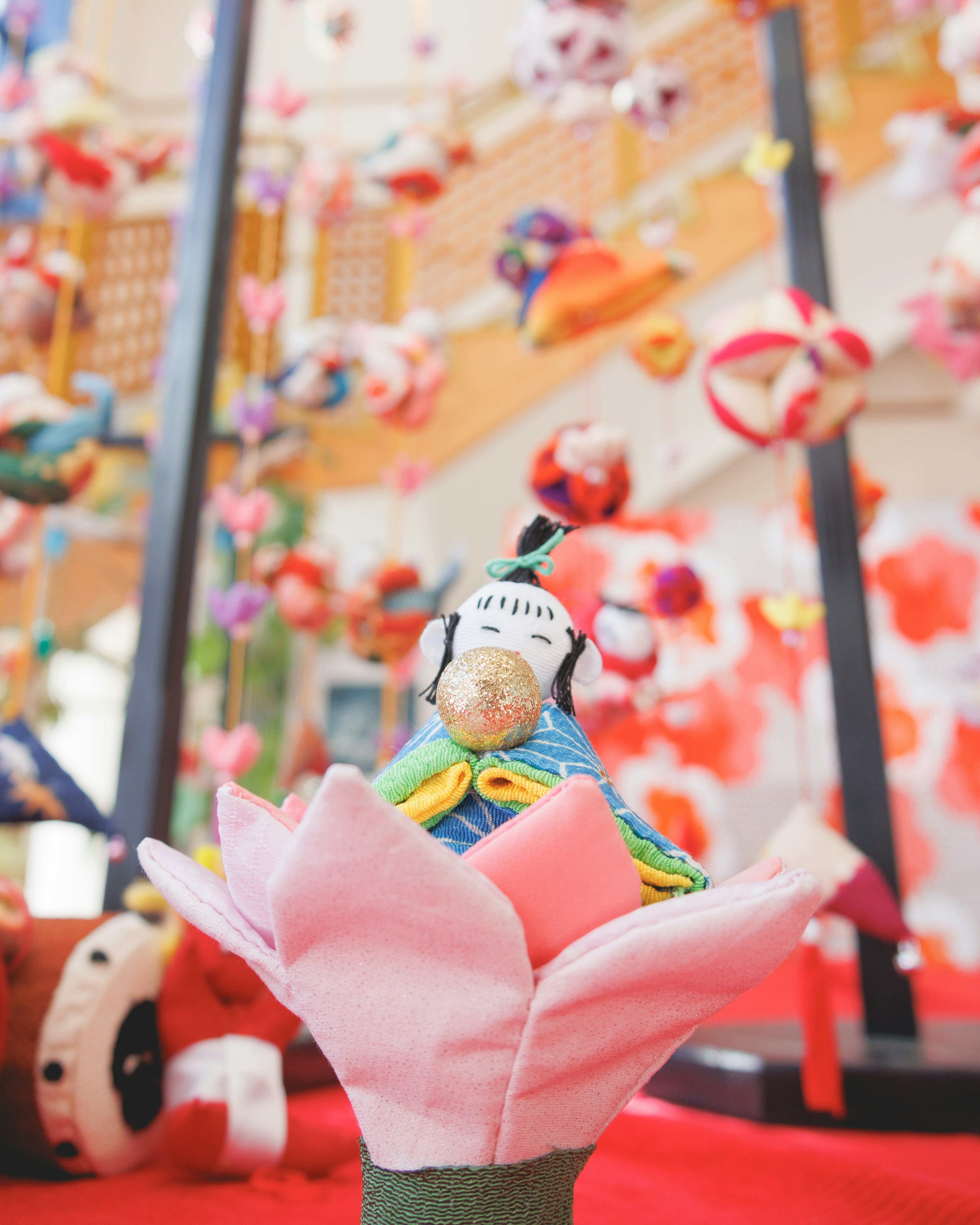 Traditional doll sitting on a beautiful flower with colorful decorations in the background