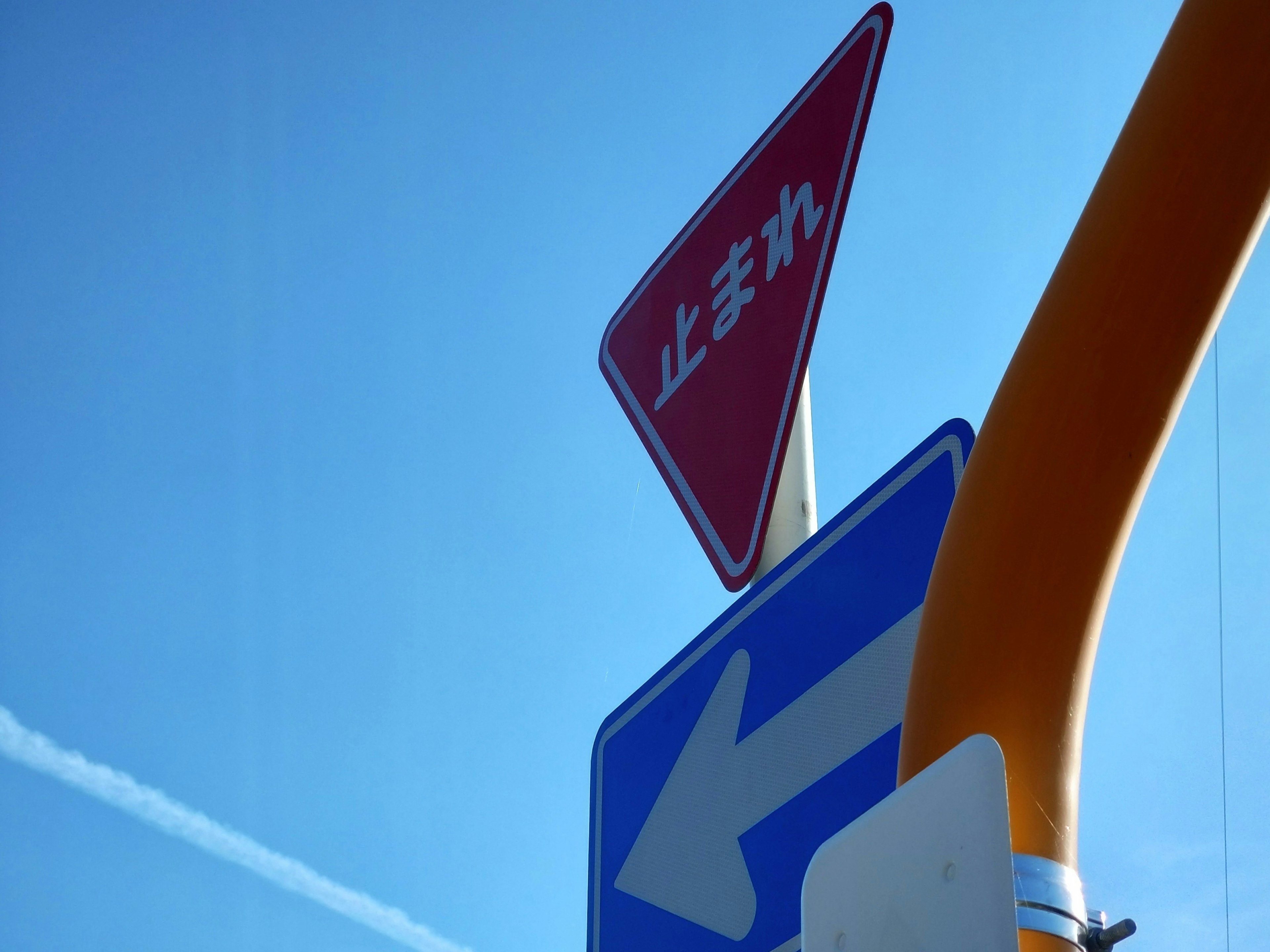 Red stop sign and blue left turn sign under a clear blue sky