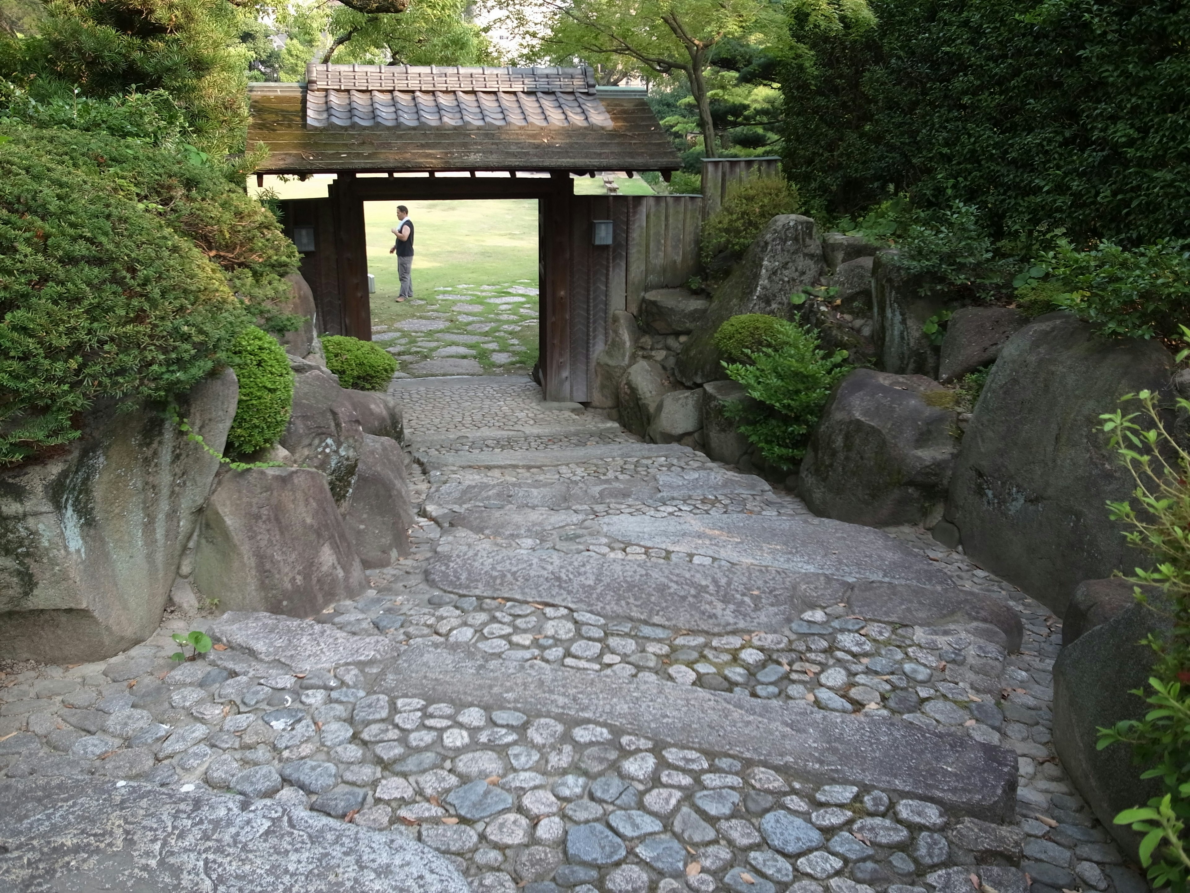 Entrada de un jardín japonés con escalones de piedra y vegetación exuberante