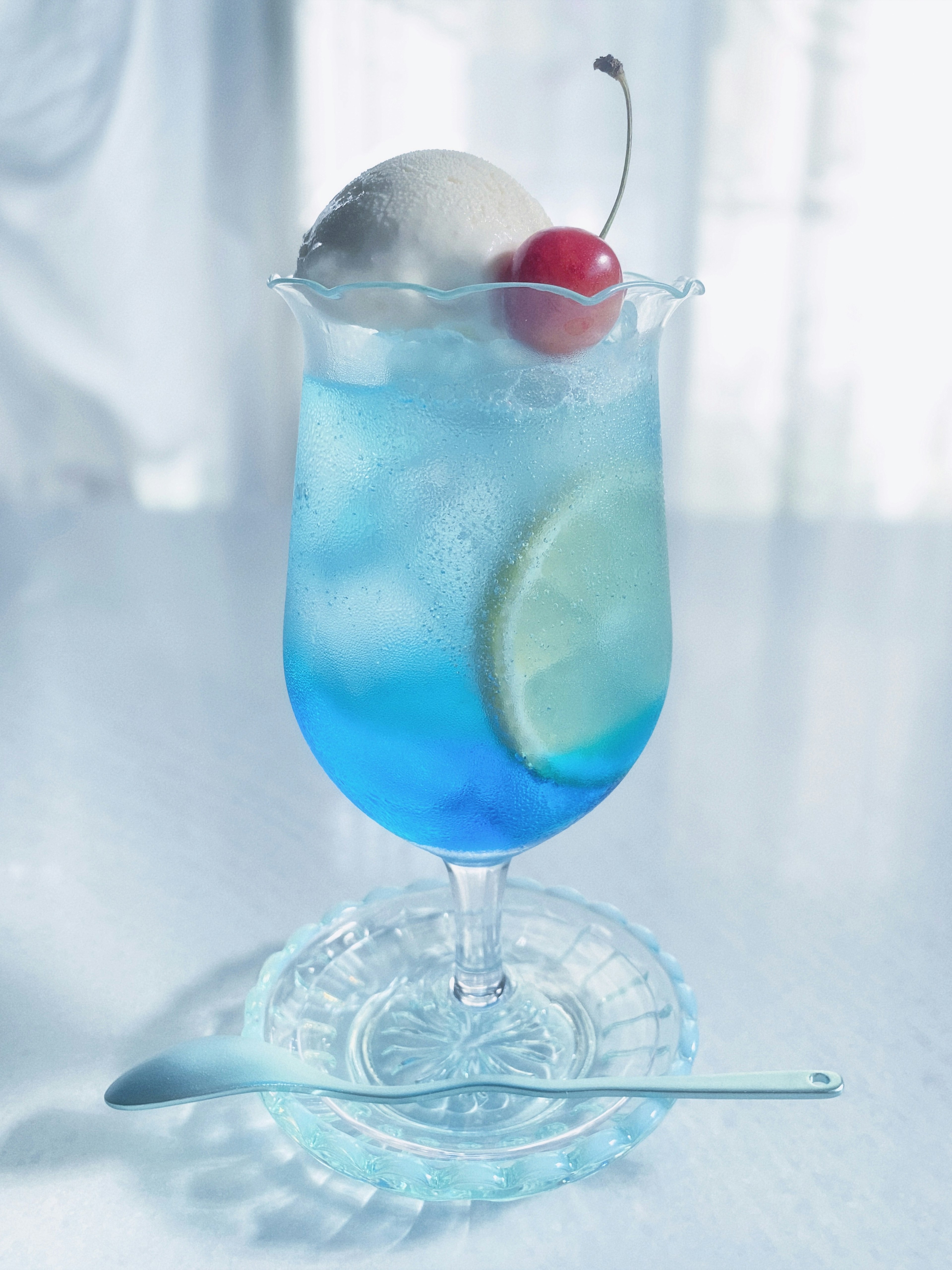 A vibrant blue cocktail topped with ice cream and a cherry