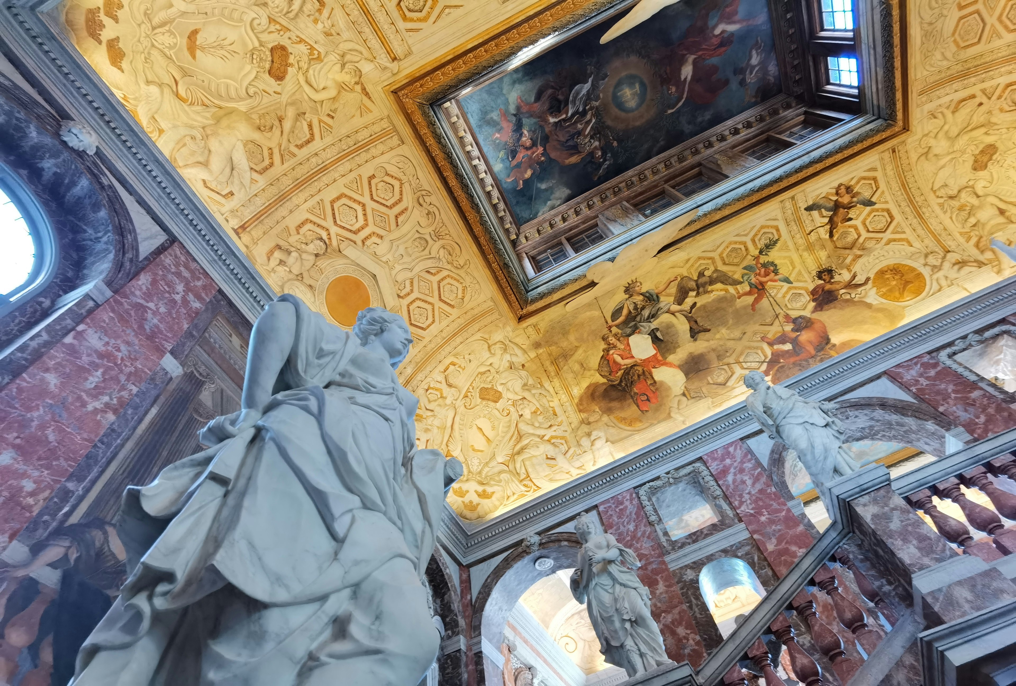 Opulent staircase featuring grand ceiling painting and sculptures