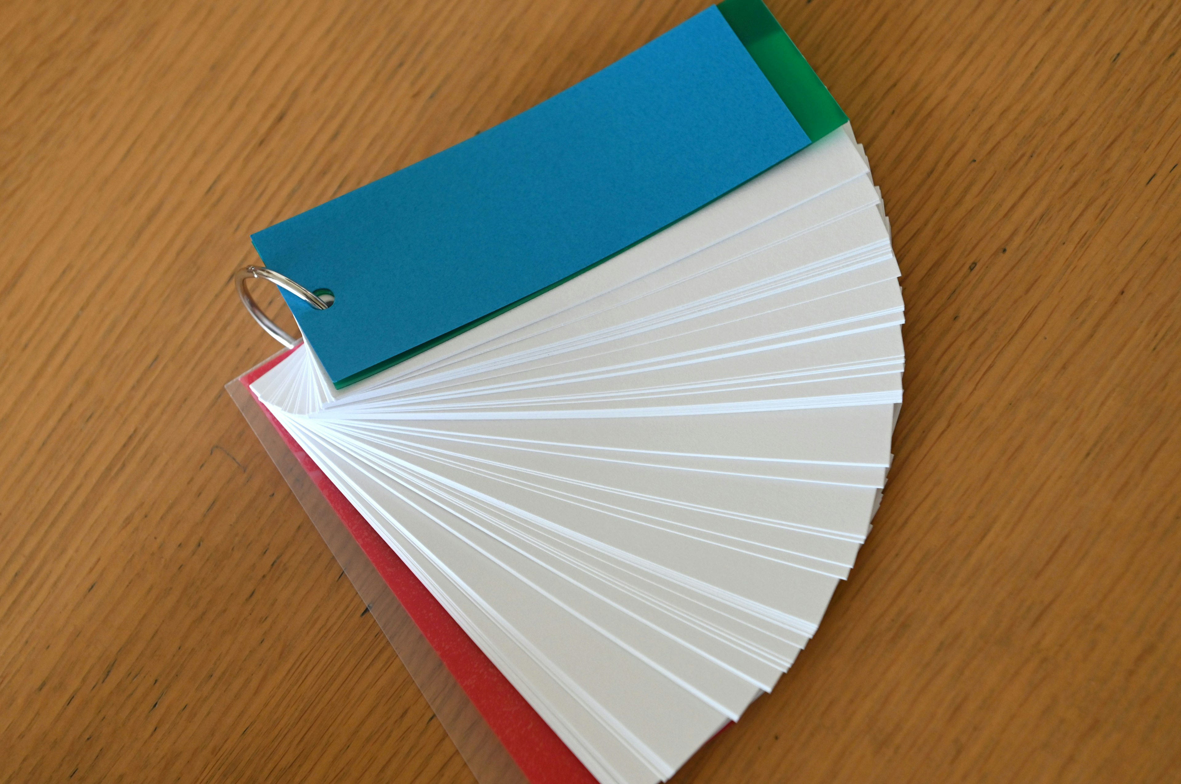 A fan of white cards with a blue tag on top resting on a wooden table