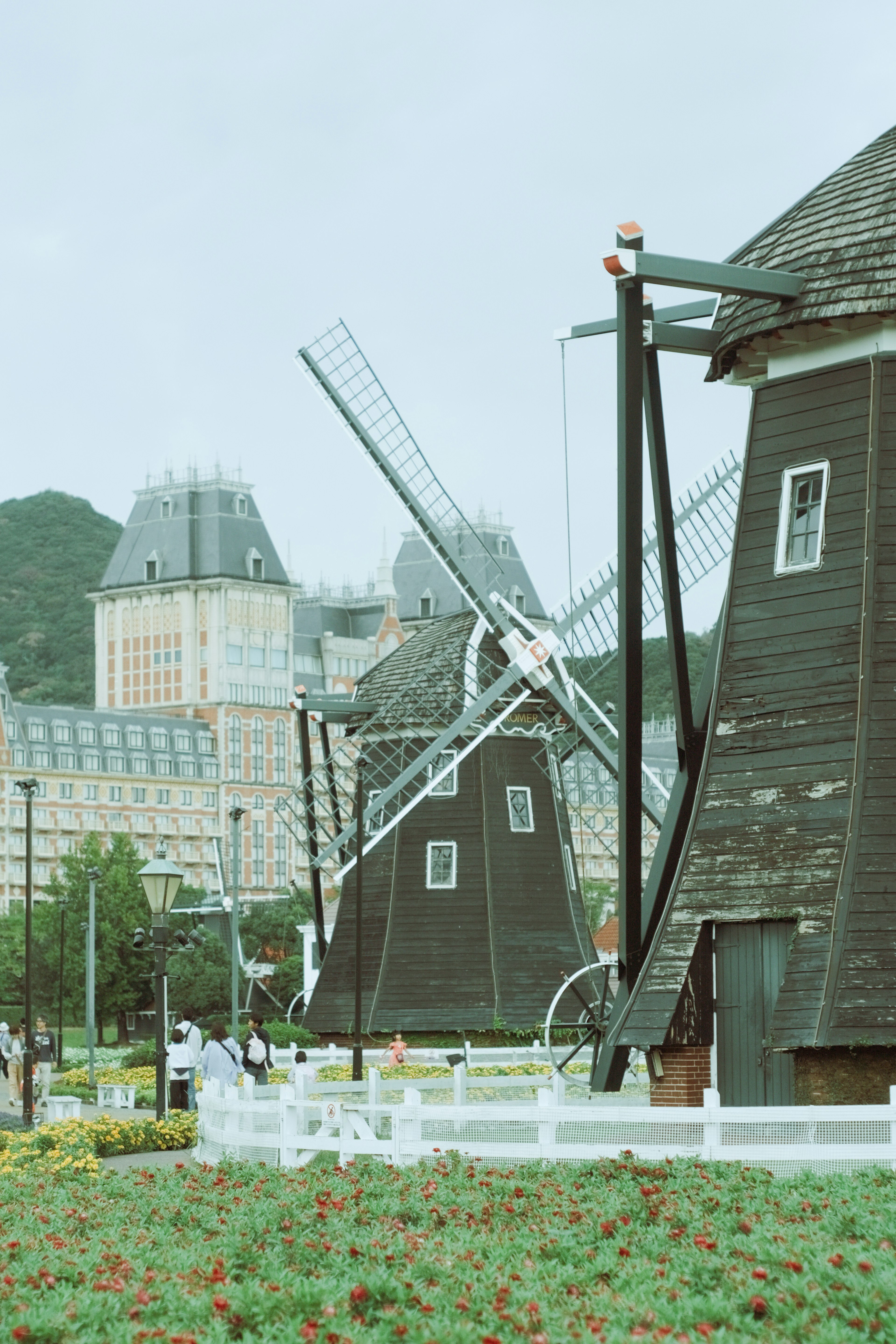 Scenic view of windmills with green grass fields and buildings in the background