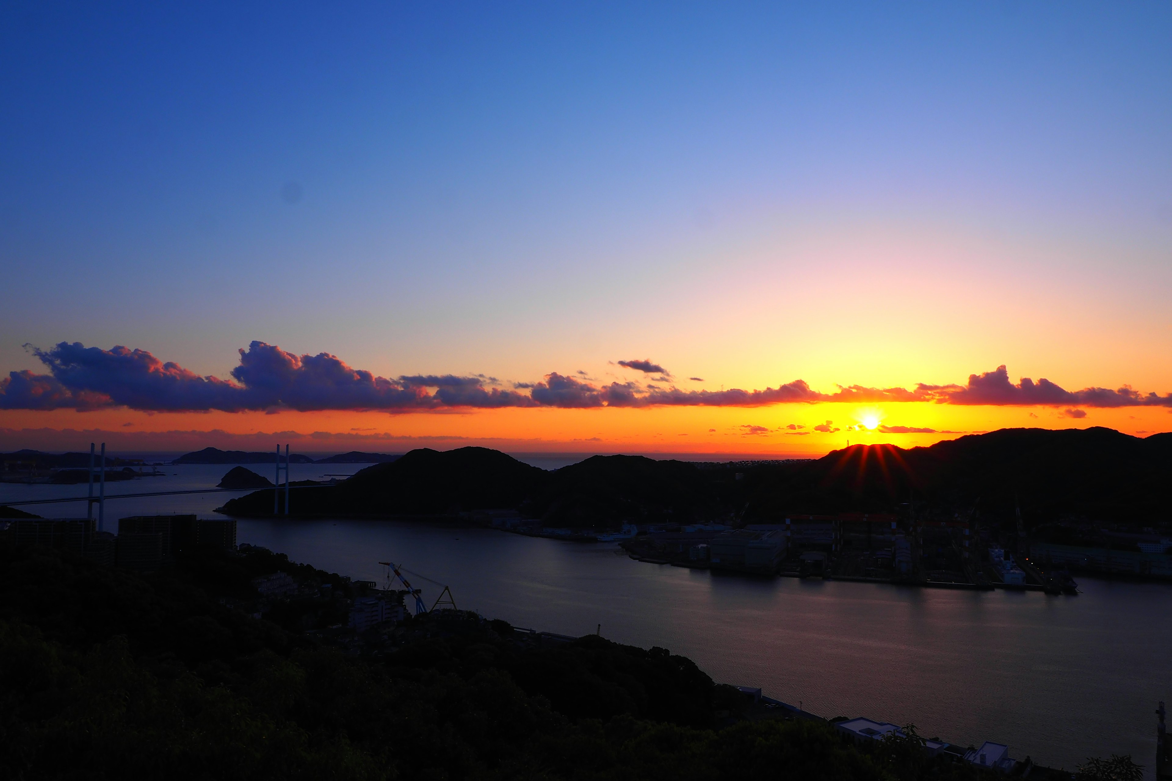 壮观的日落景色，宁静的海面和山丘