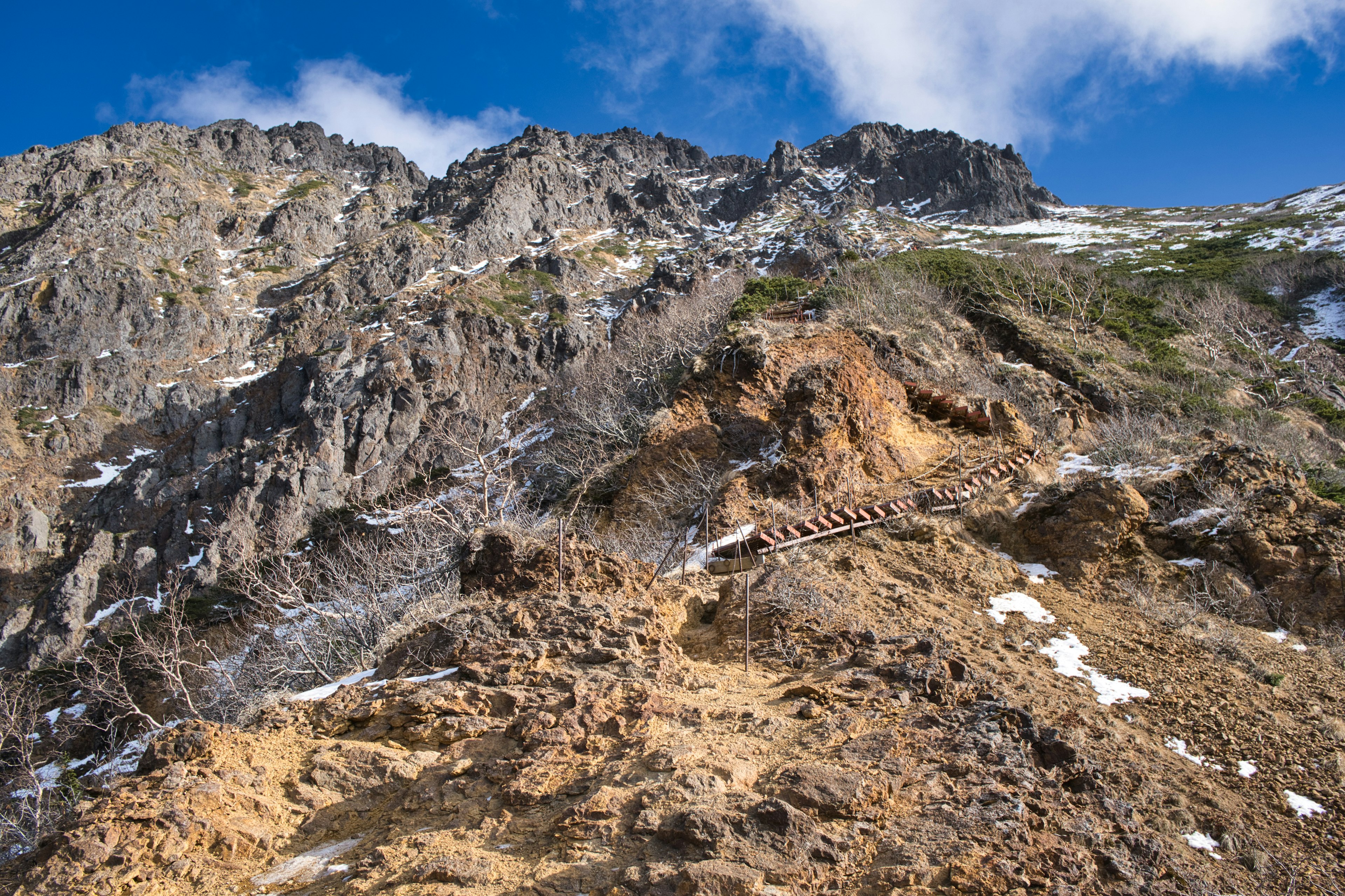 Vue panoramique d'une montagne imposante avec un ciel bleu terrain rocheux et taches de neige