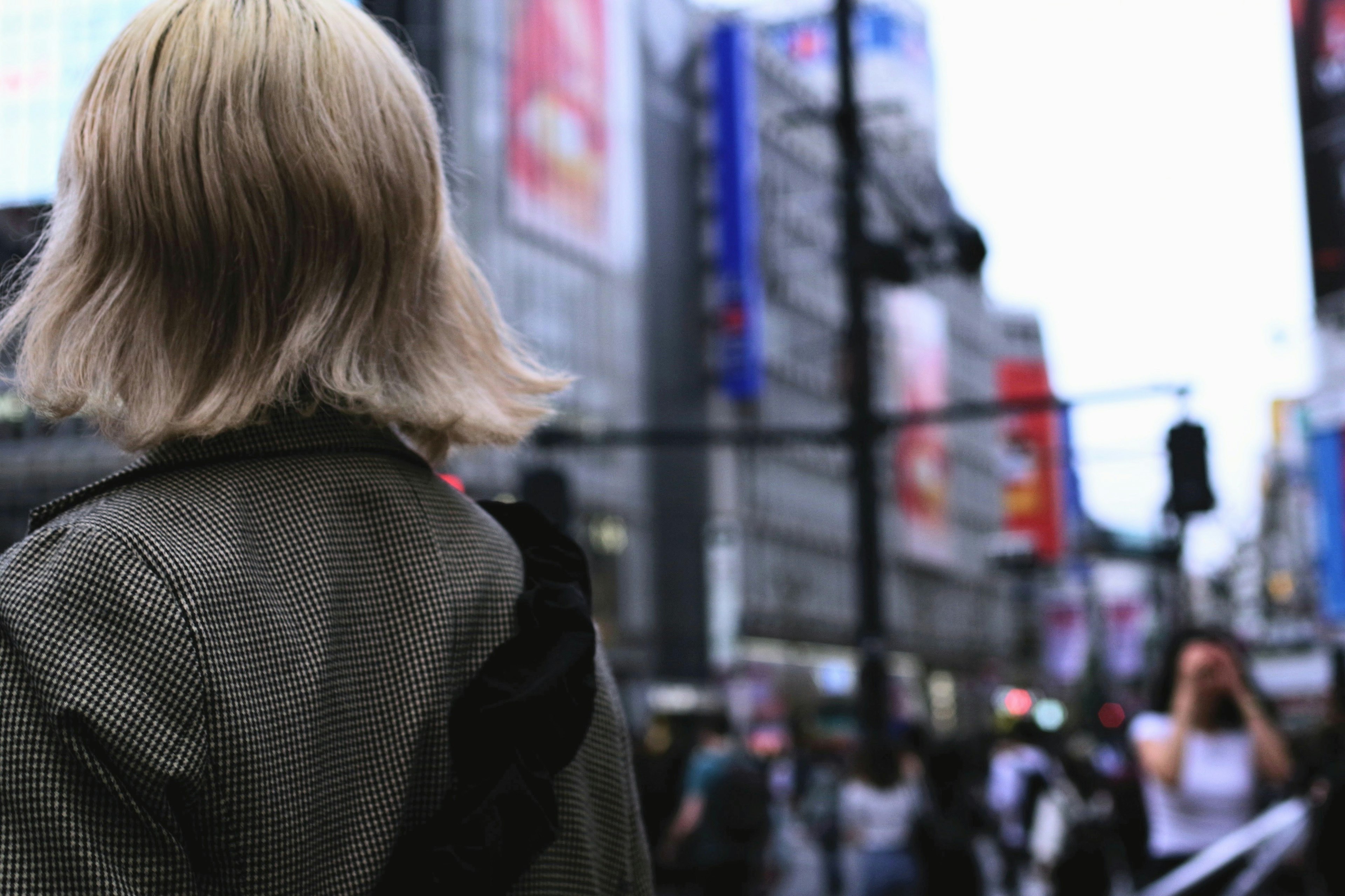 A blonde person seen from behind in an urban setting