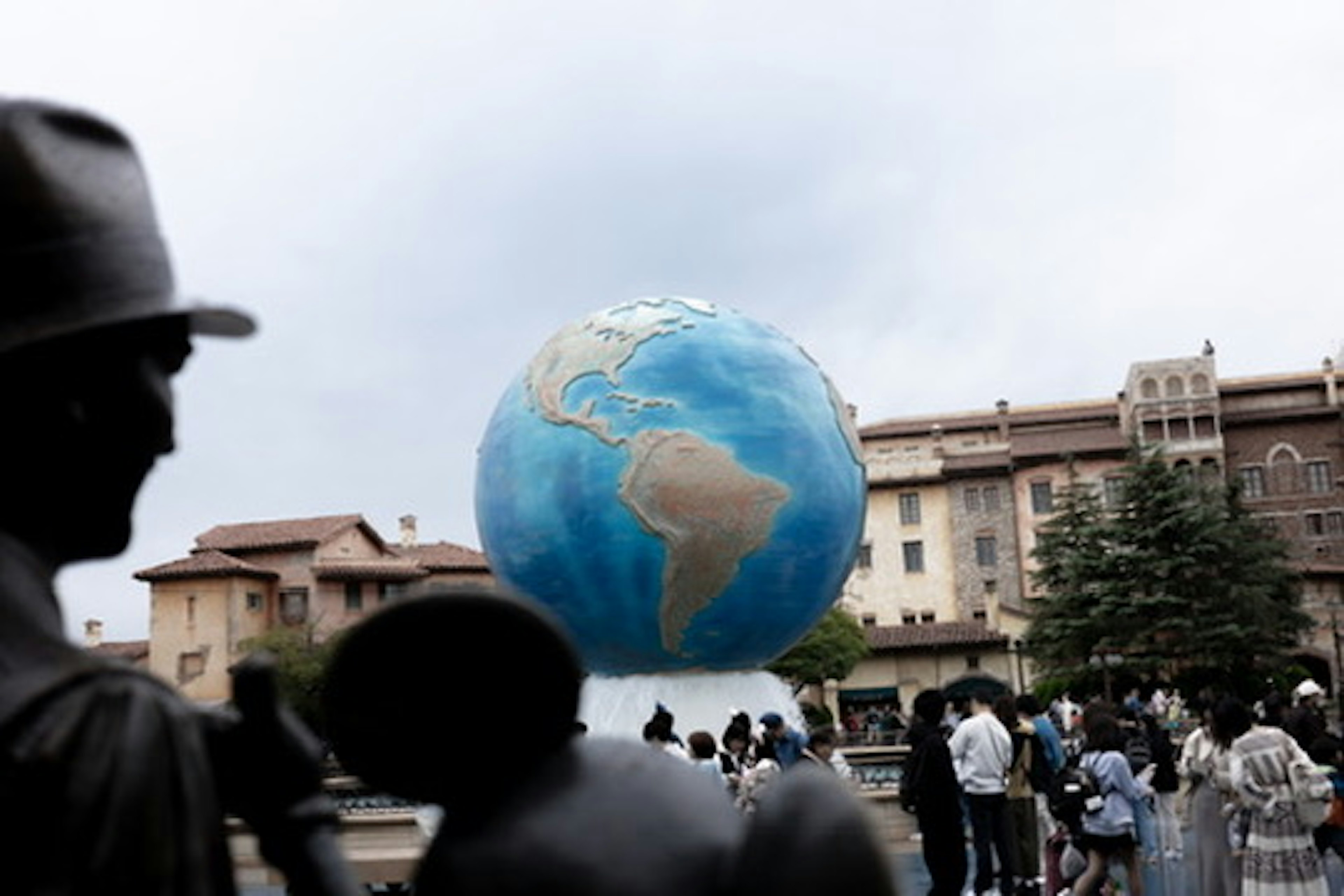 青い地球のオブジェと人々が集まる広場の風景