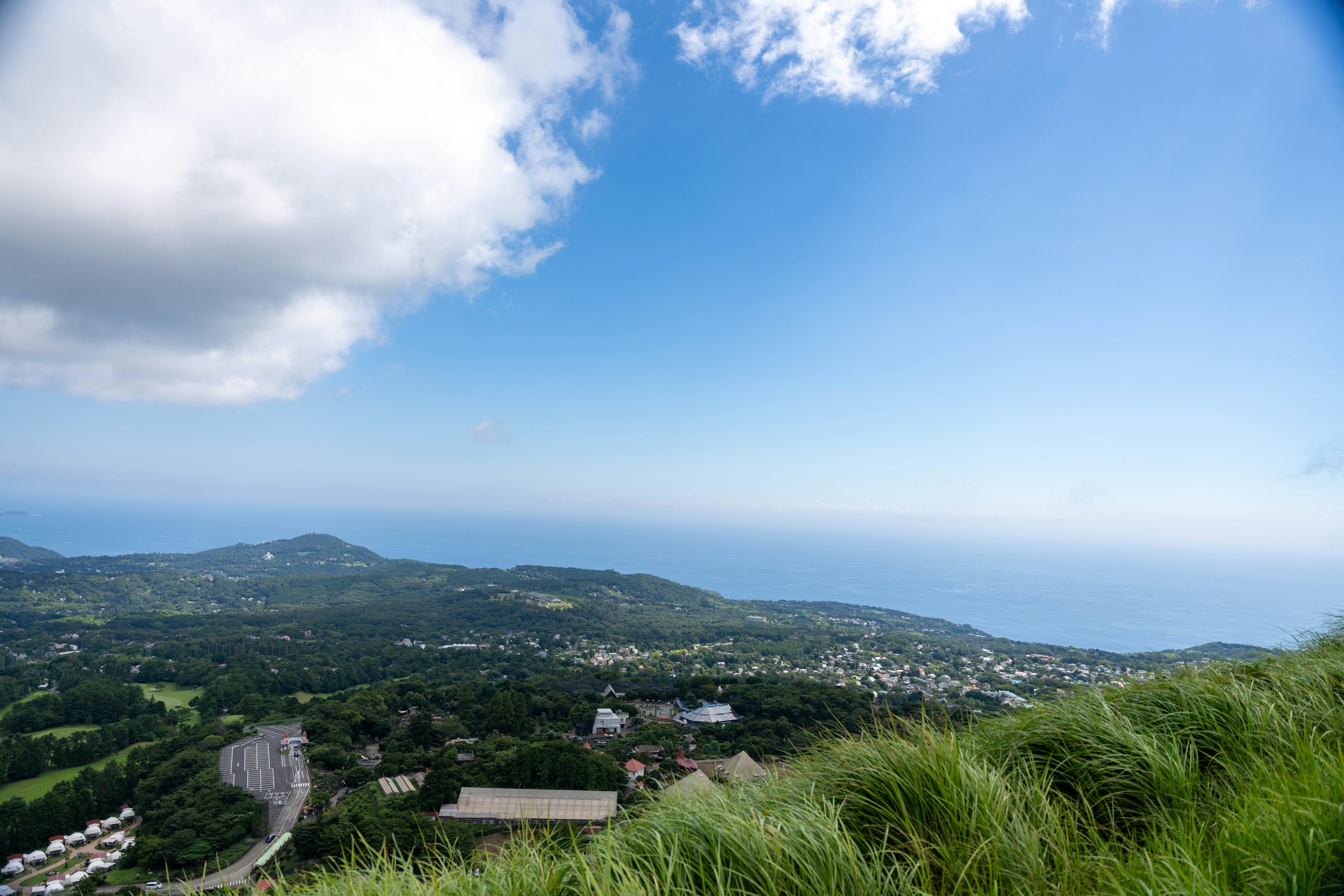 Panoramablick auf grüne Hügel und Ozean unter blauem Himmel mit Wolken