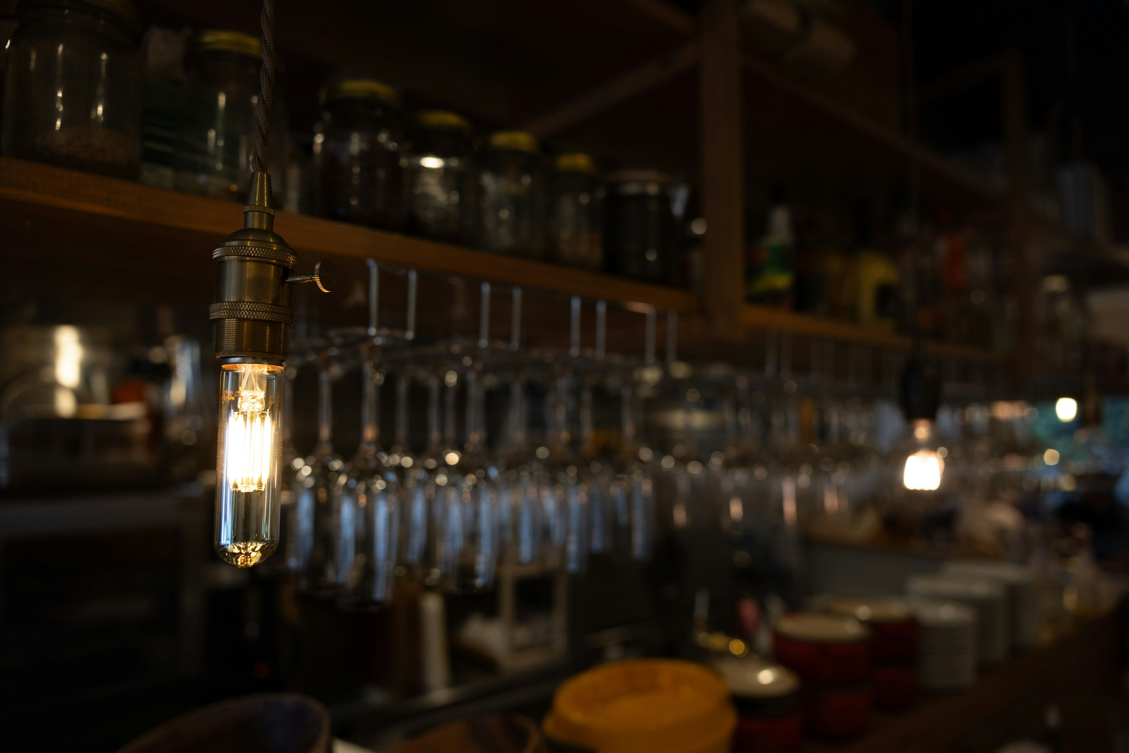Interior de un café con luces colgantes y estantes de tarros de vidrio