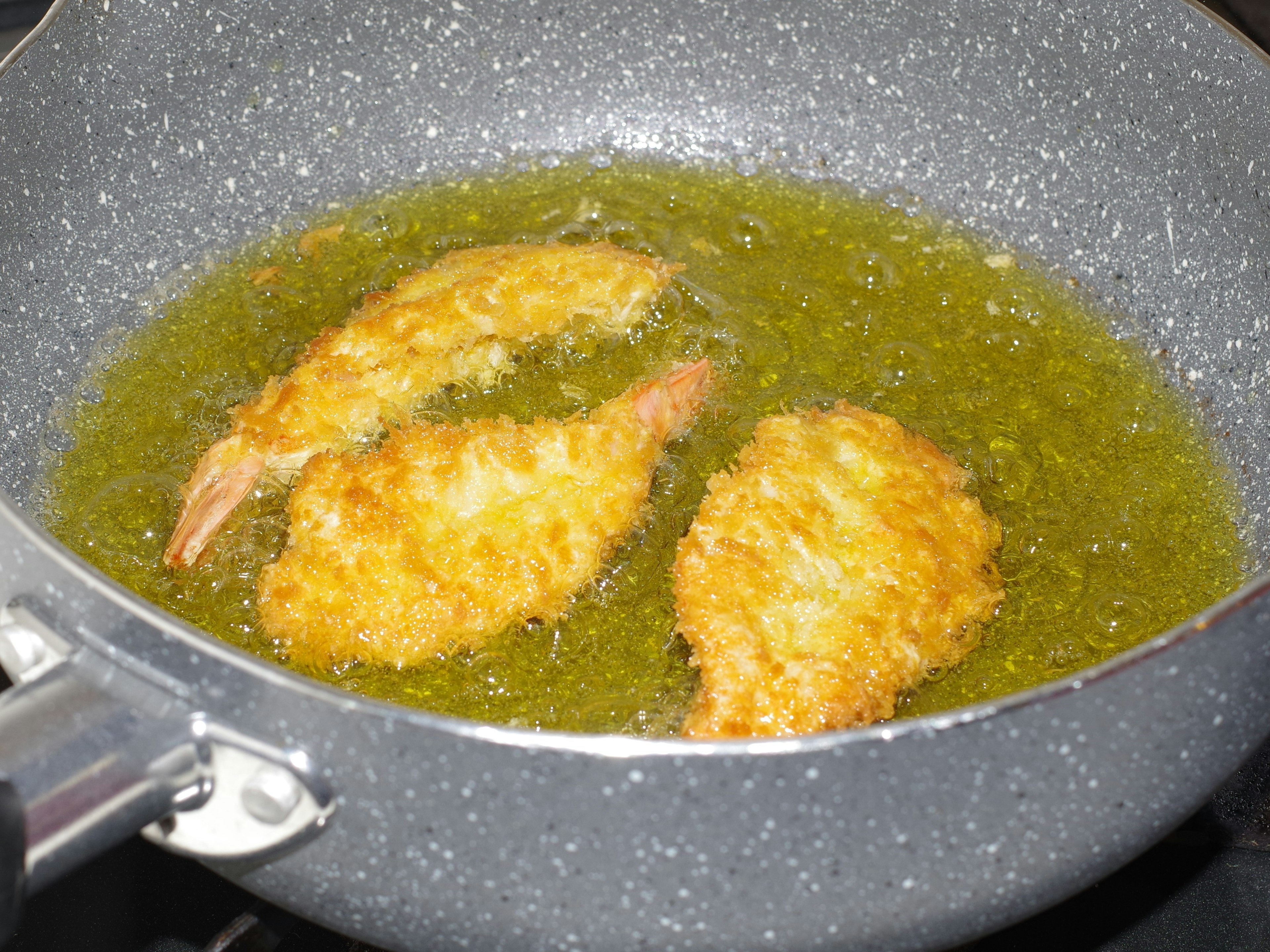 Gamberetti fritti in cottura nell'olio in una padella