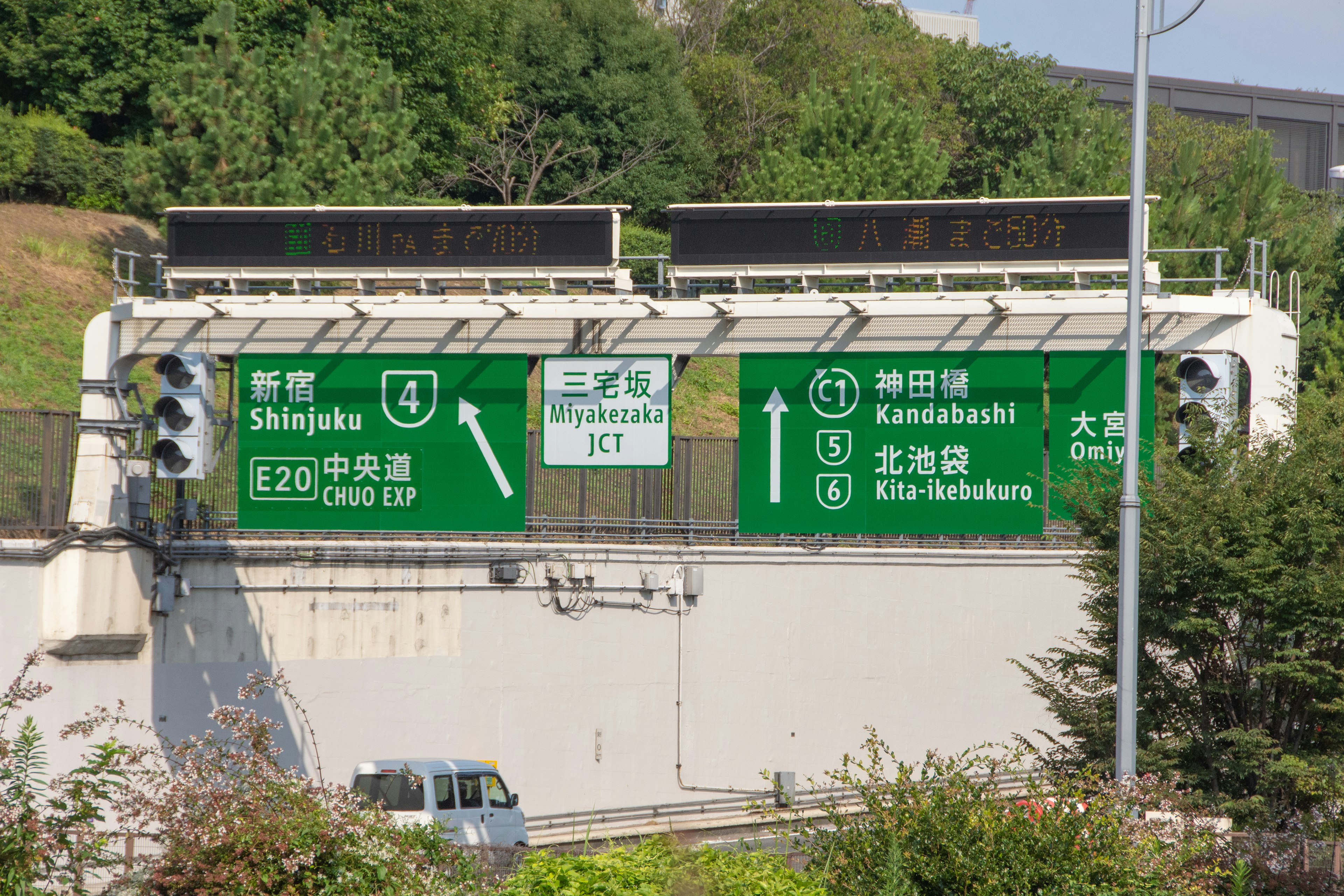 Green highway signs with directional indicators on a roadway