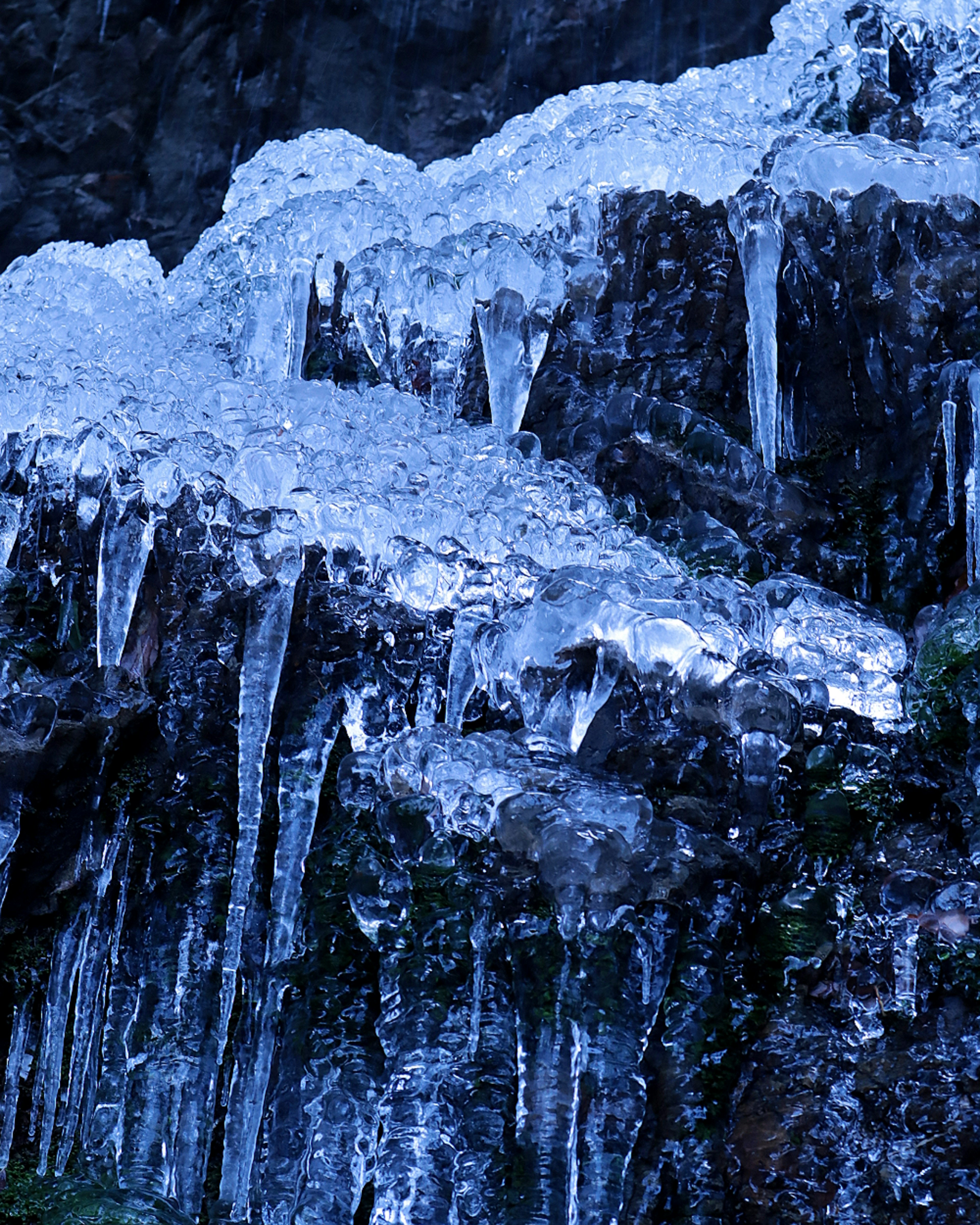 氷の滝の近景、青い氷のつららと岩のコントラスト