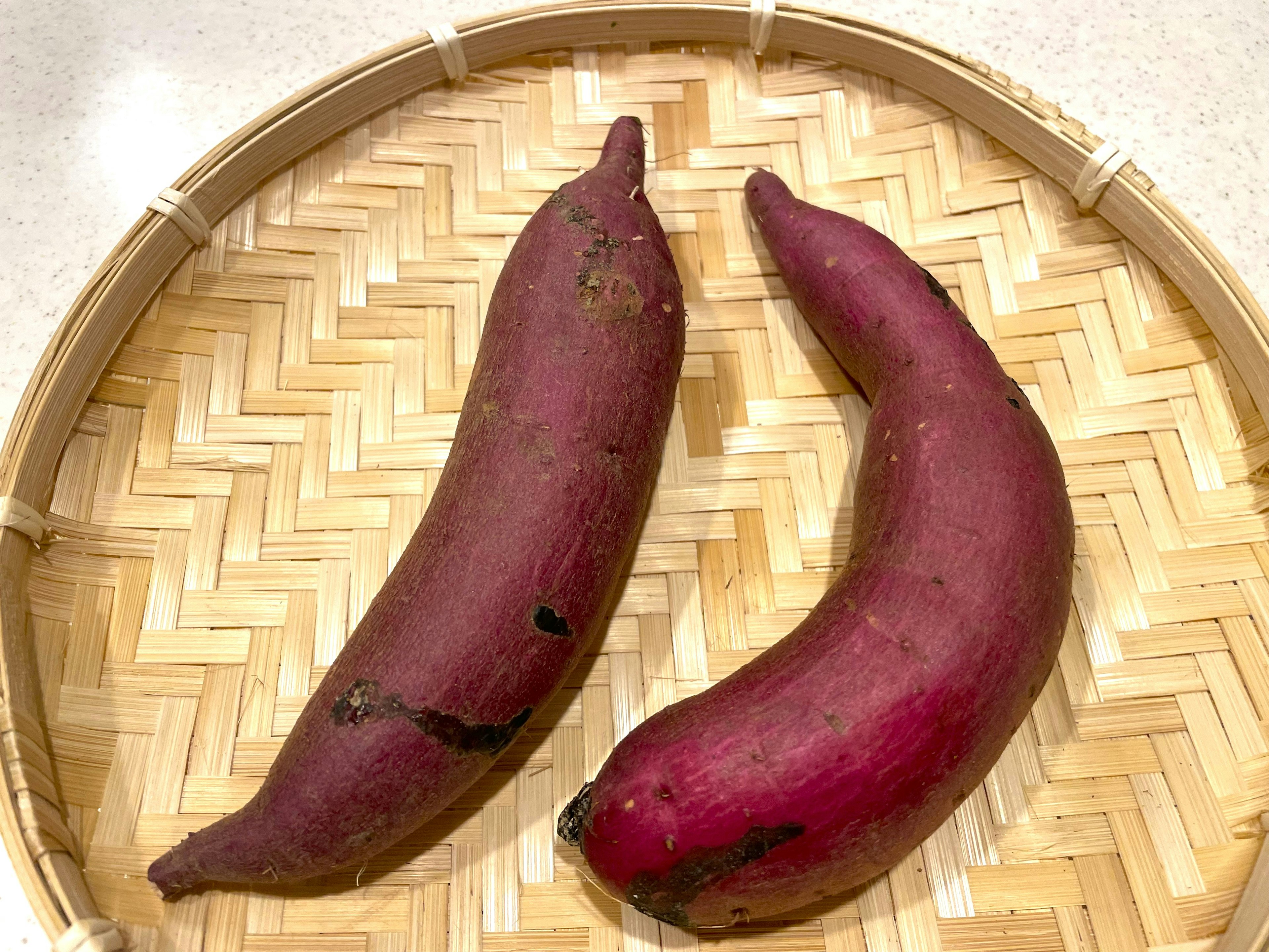 Two purple sweet potatoes on a bamboo basket