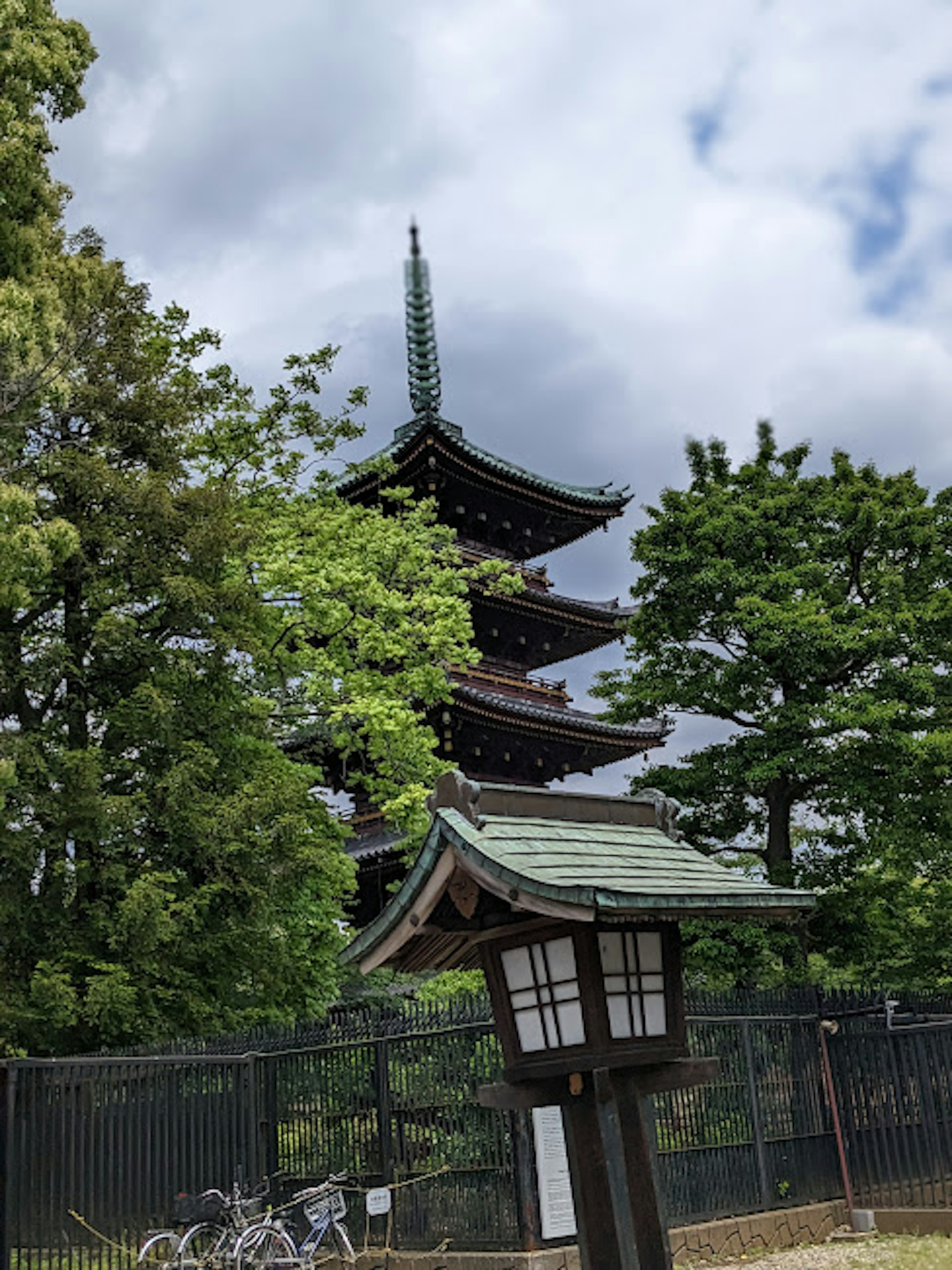 Pagode à cinq étages entourée d'arbres verts et d'une lanterne