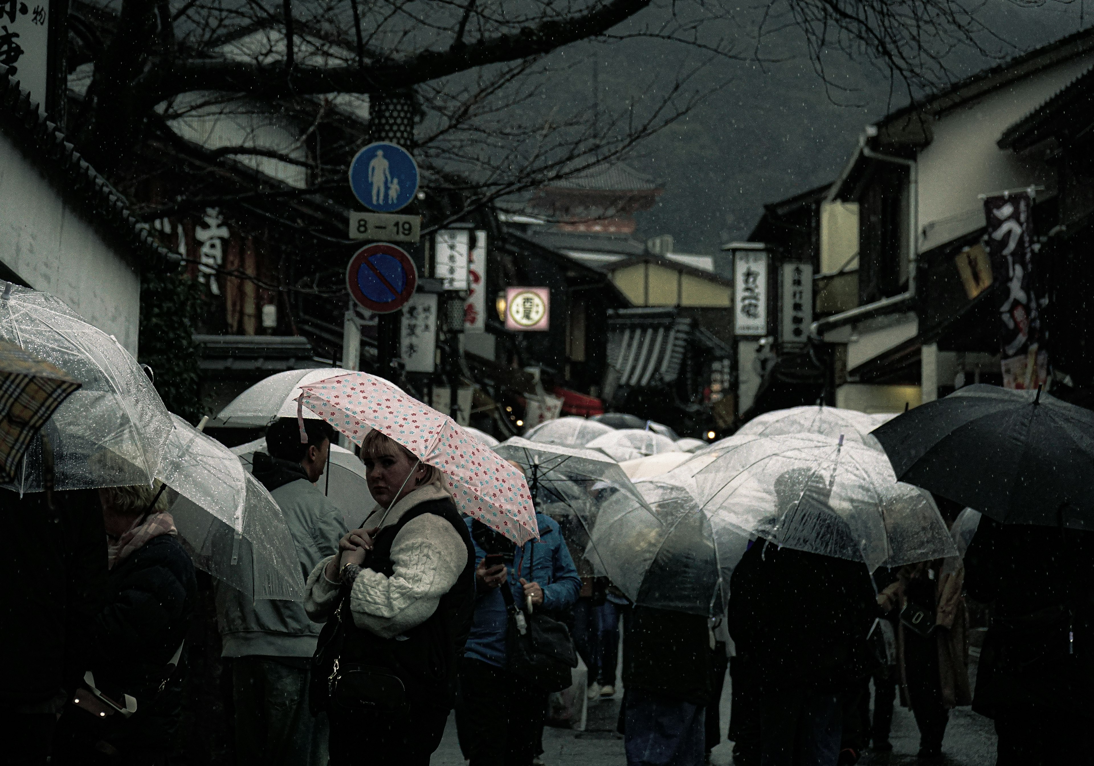 雨の中を歩く人々が傘を持っている古い街並み