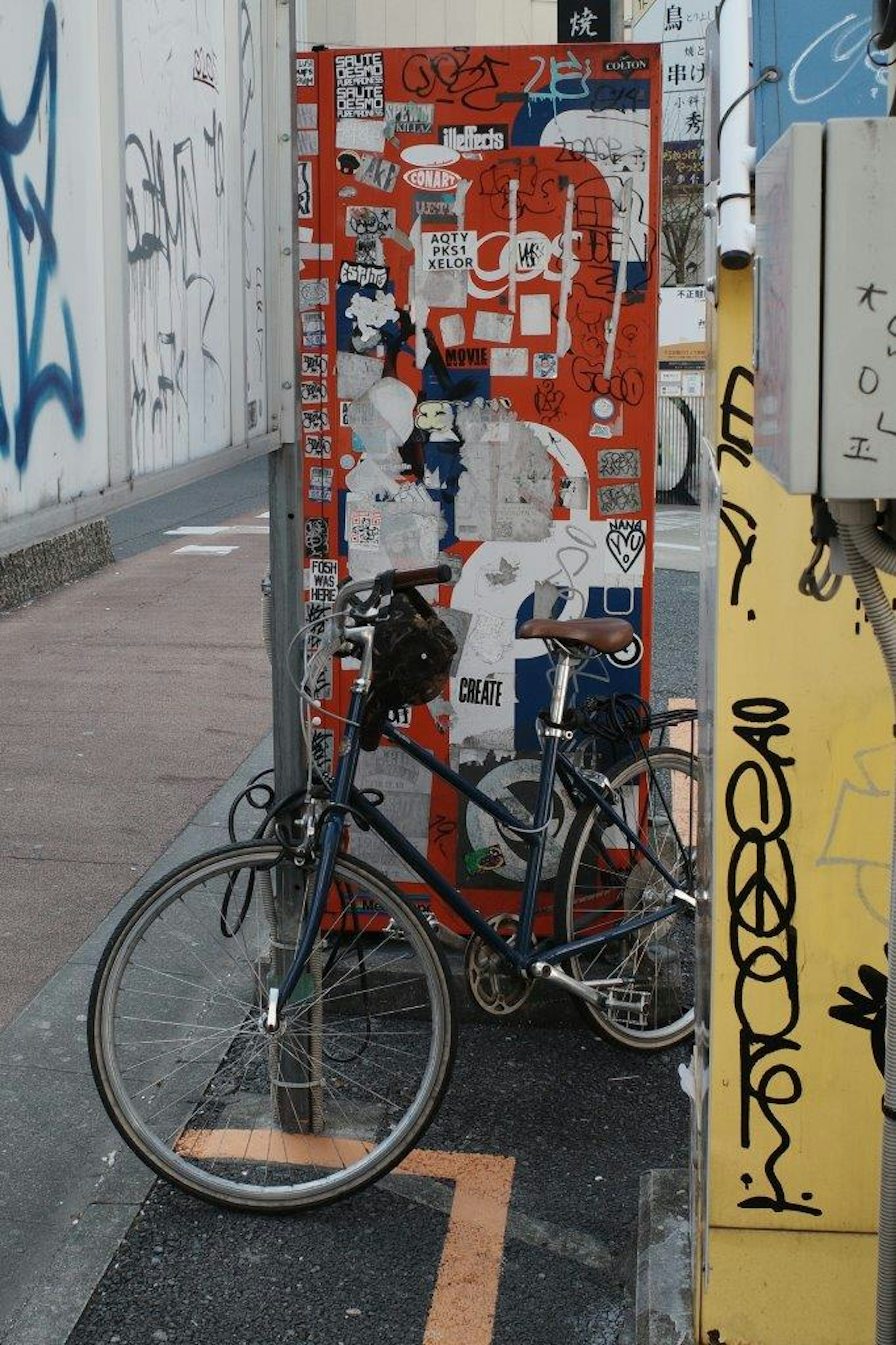 Bicycle parked in front of a wall covered with red and blue graffiti