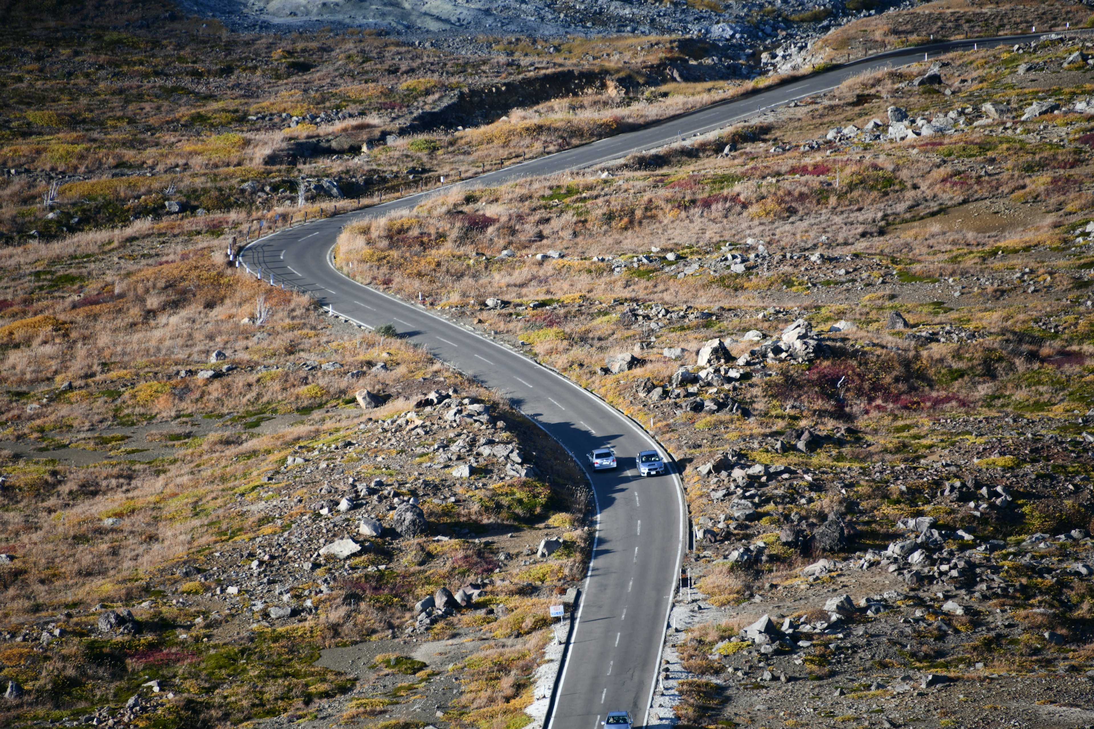 Una carretera de montaña serpenteante rodeada de rocas y hierba