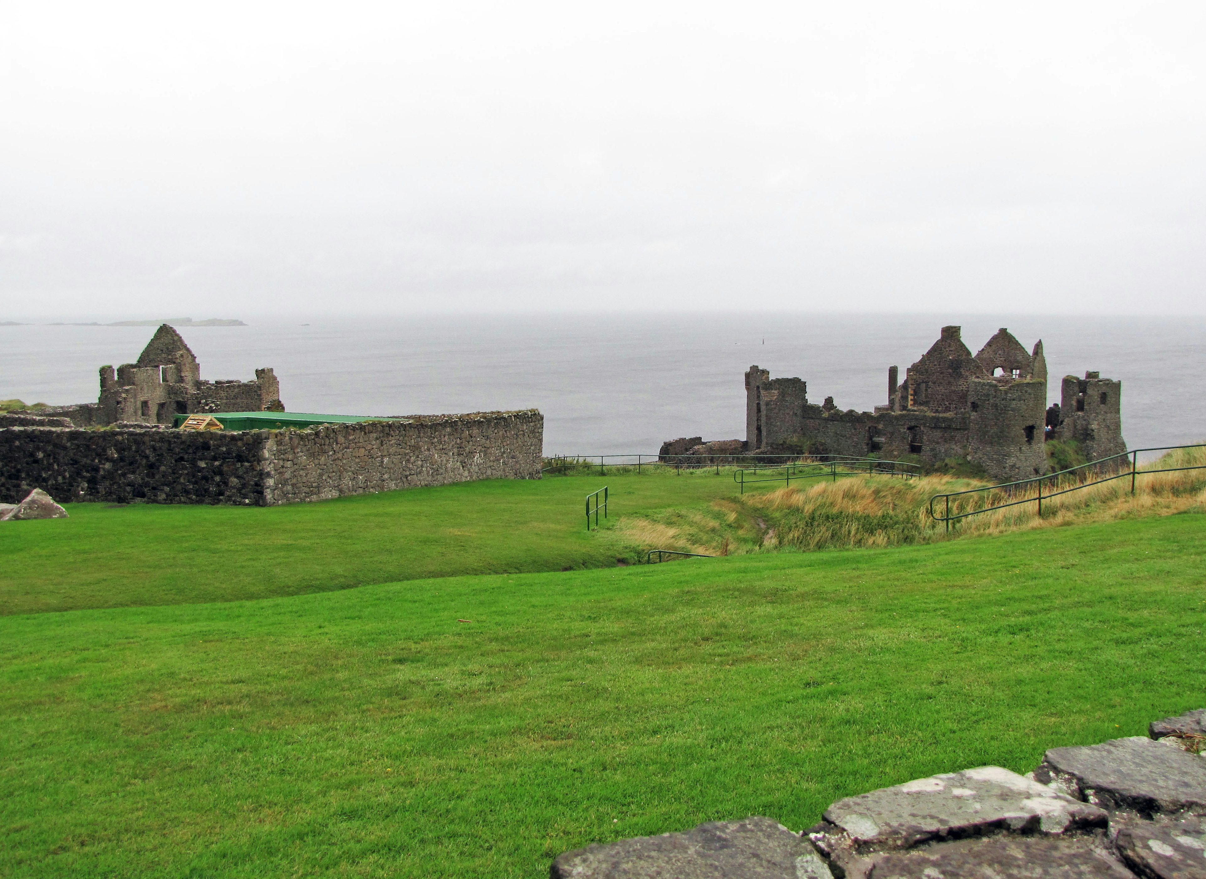 Ruins of an old castle against a backdrop of green grass and the sea