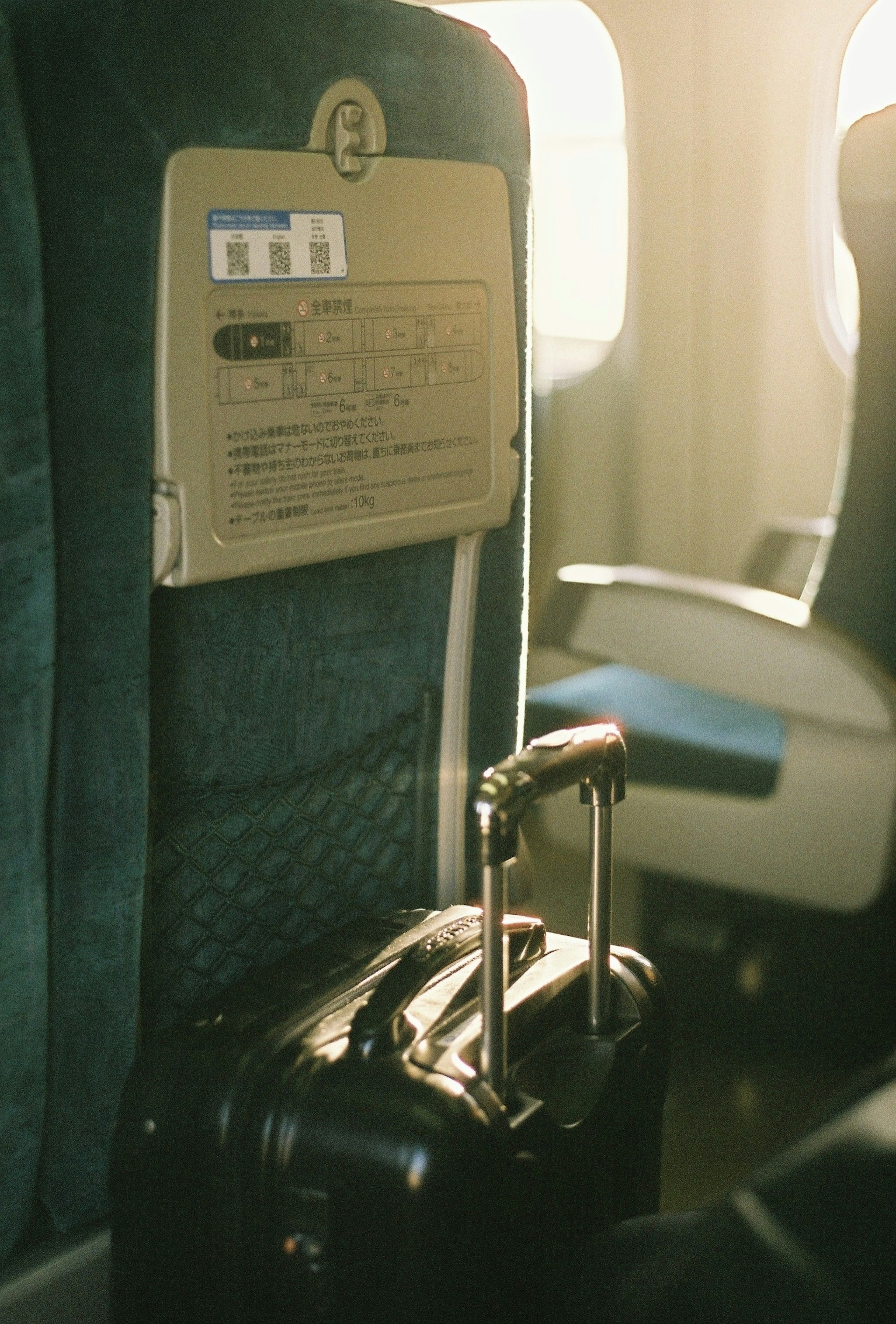 Photo of an airplane seat and suitcase with bright light coming through