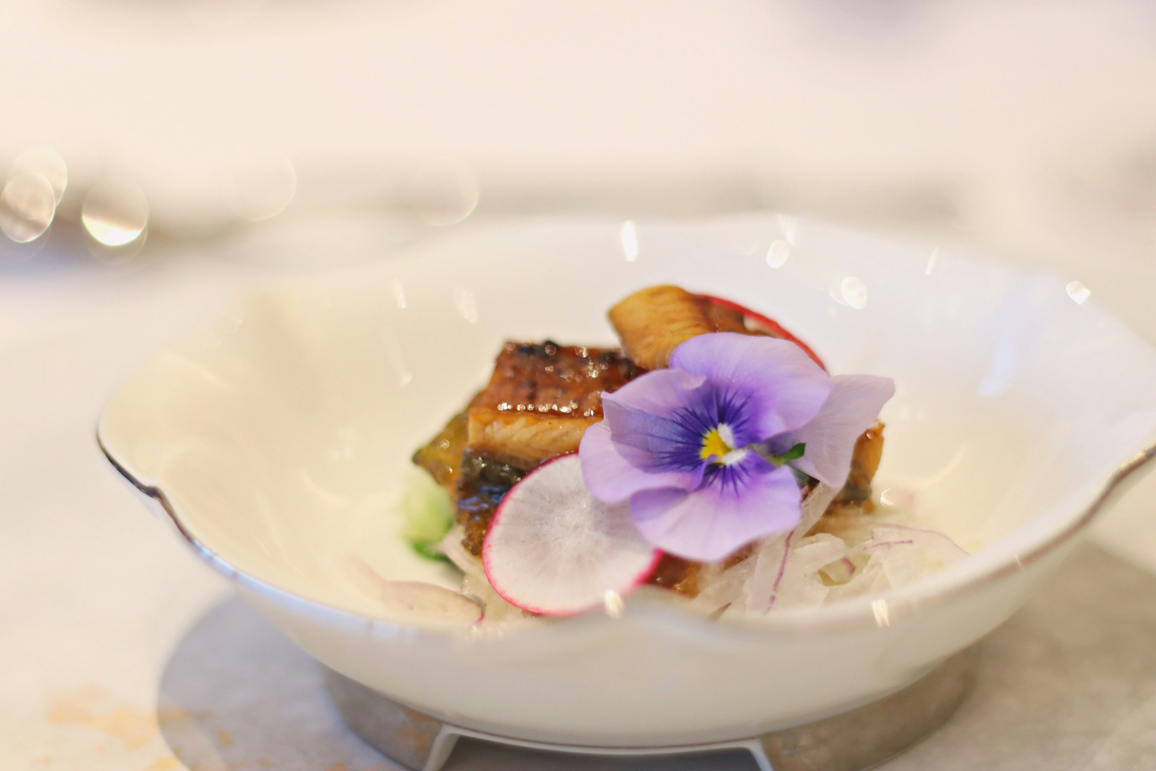 Un plat joliment présenté avec une garniture de fleur violette