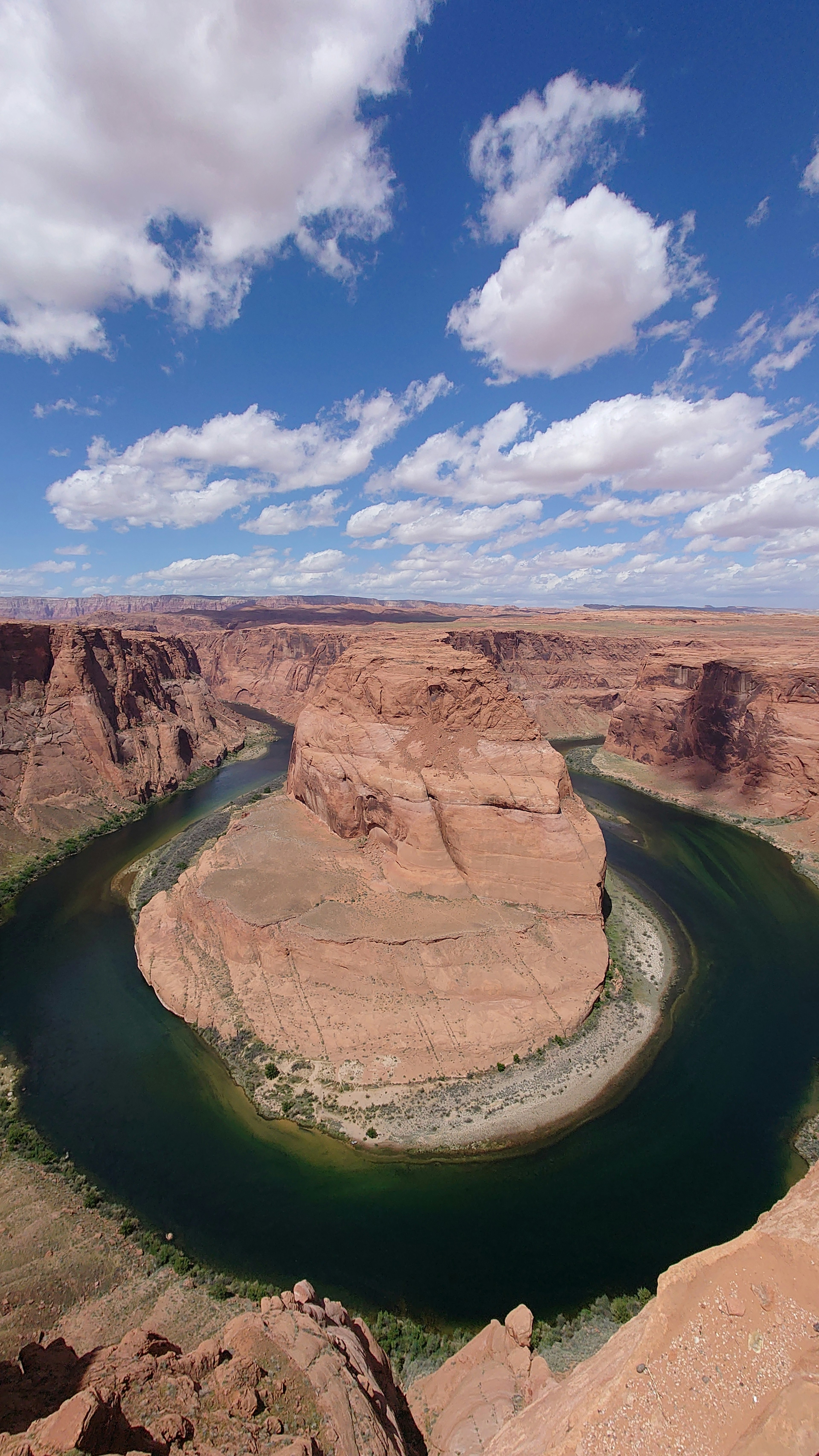 Impresionante vista de Horseshoe Bend con cielo azul y nubes blancas río verde y formaciones rocosas rojas