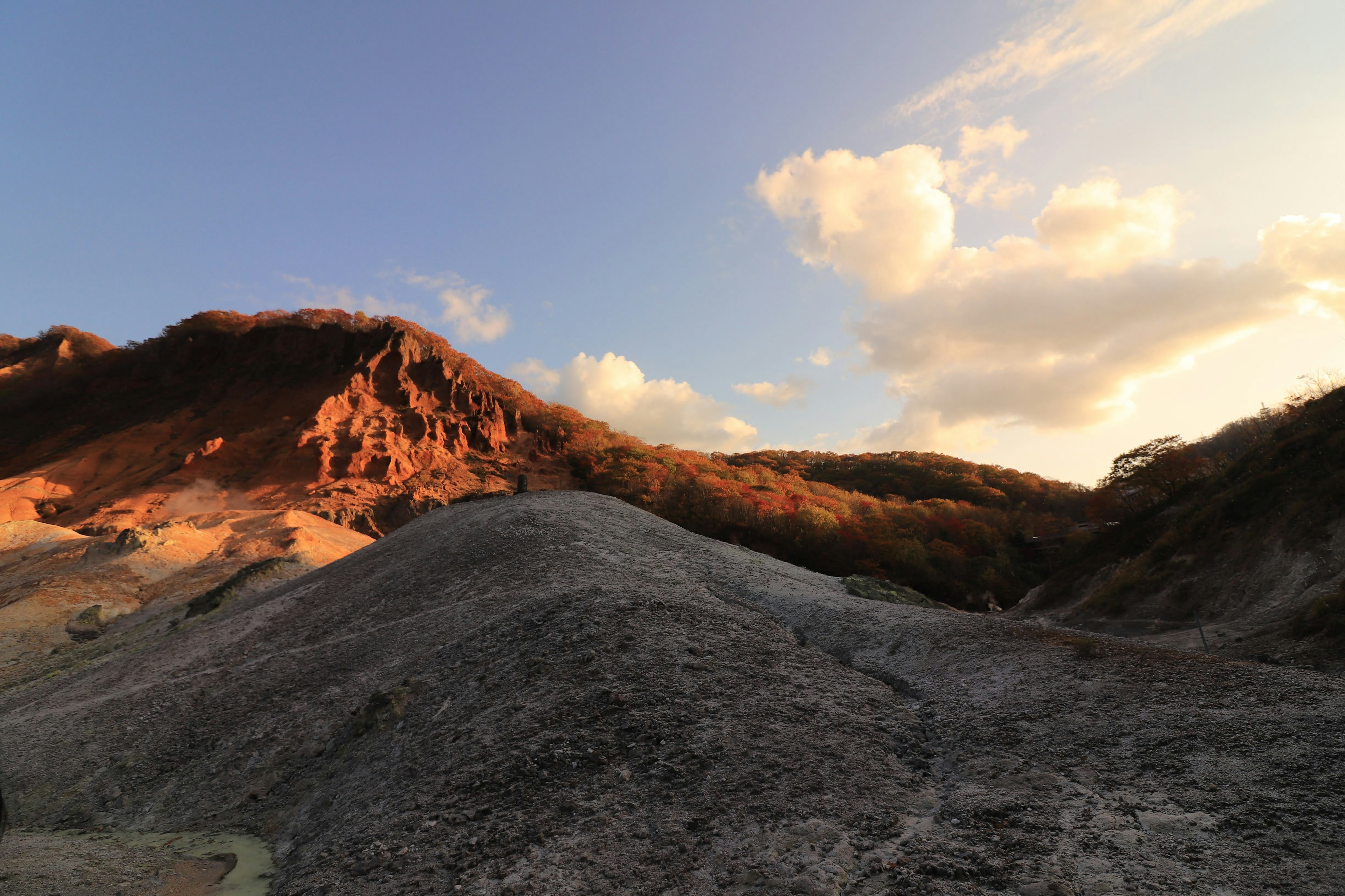 Landschaft von Bergen, die vom Sonnenuntergang beleuchtet werden, mit grauem Terrain