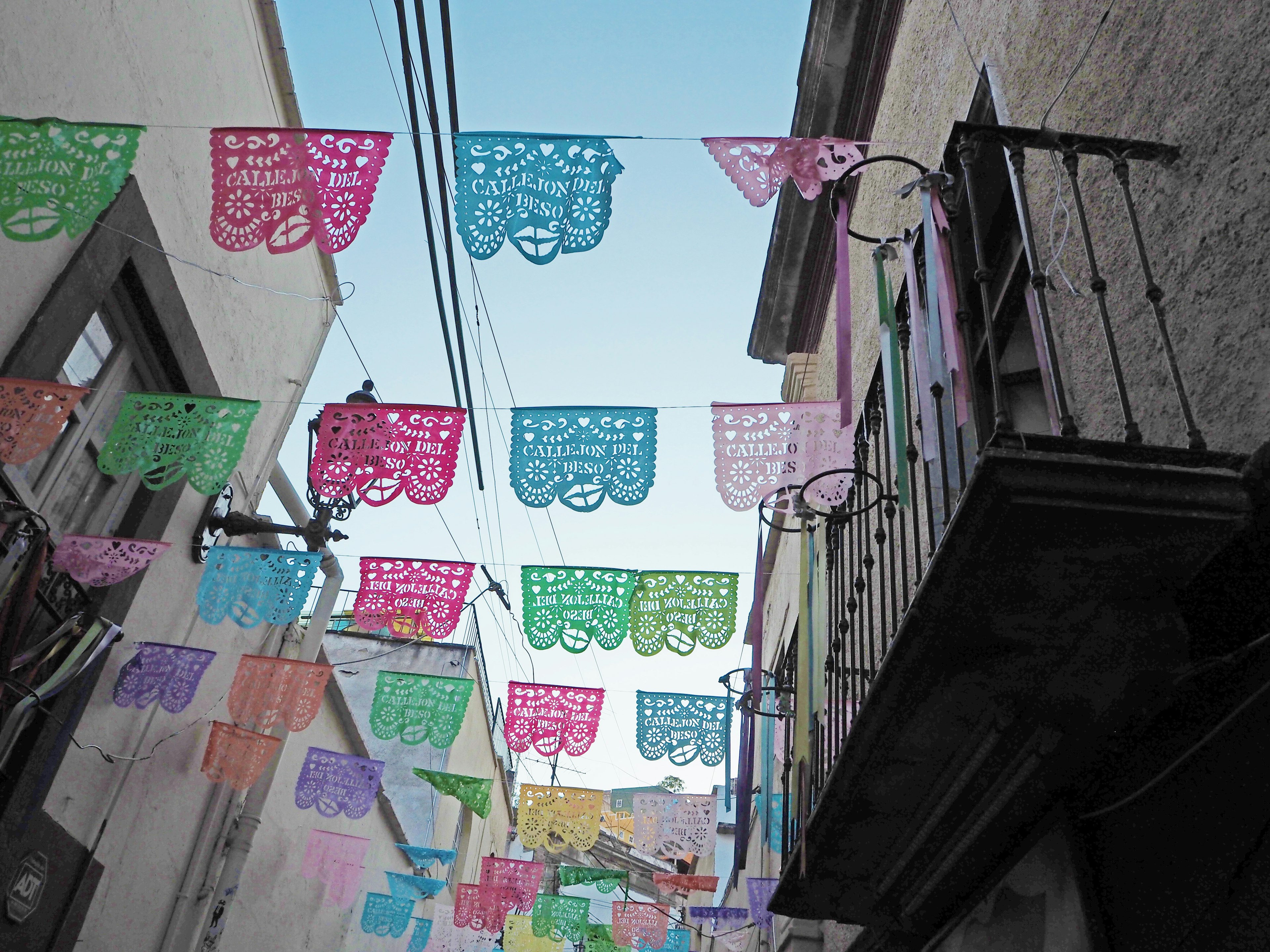 Banderas de papel picado coloridas colgando en una calle estrecha