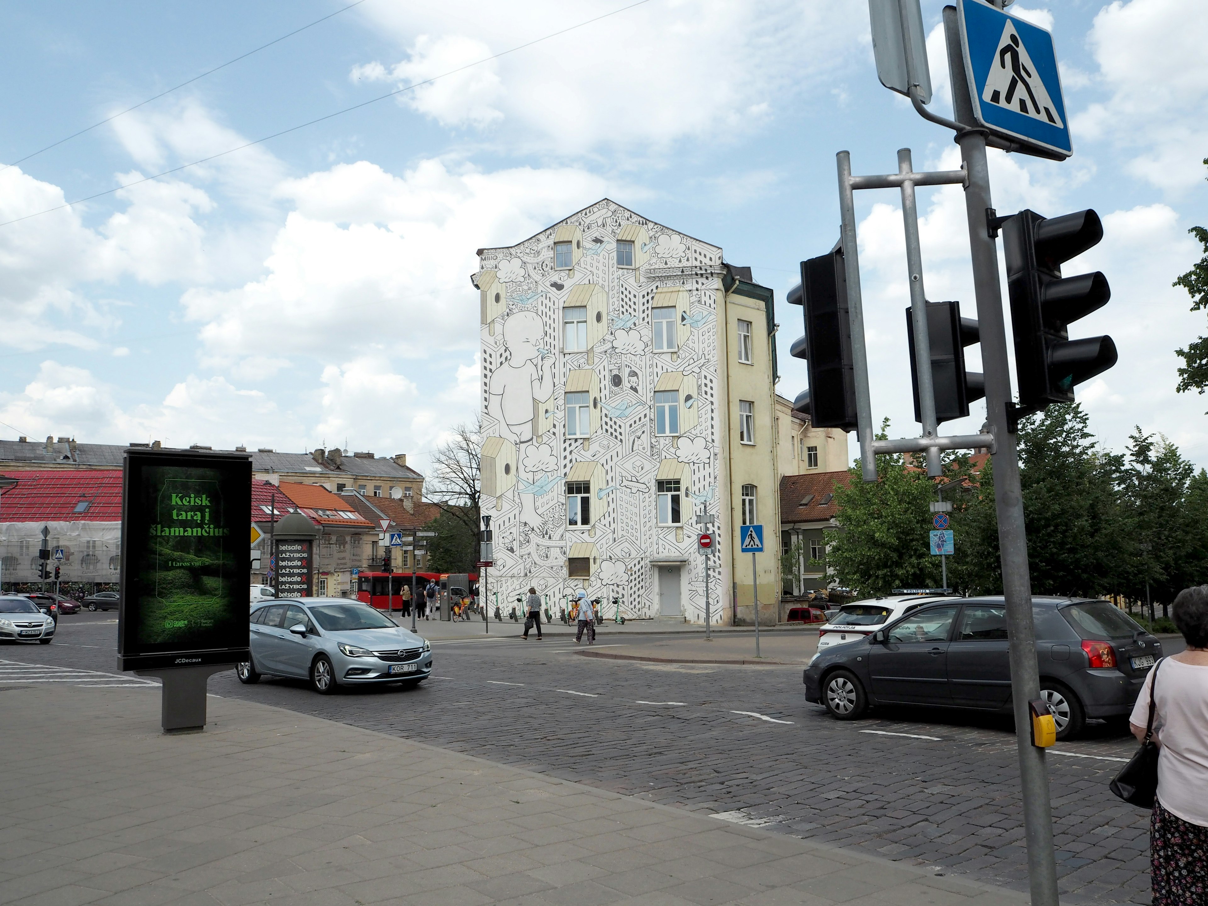 Bâtiment unique à façade blanche à un carrefour avec des feux de circulation