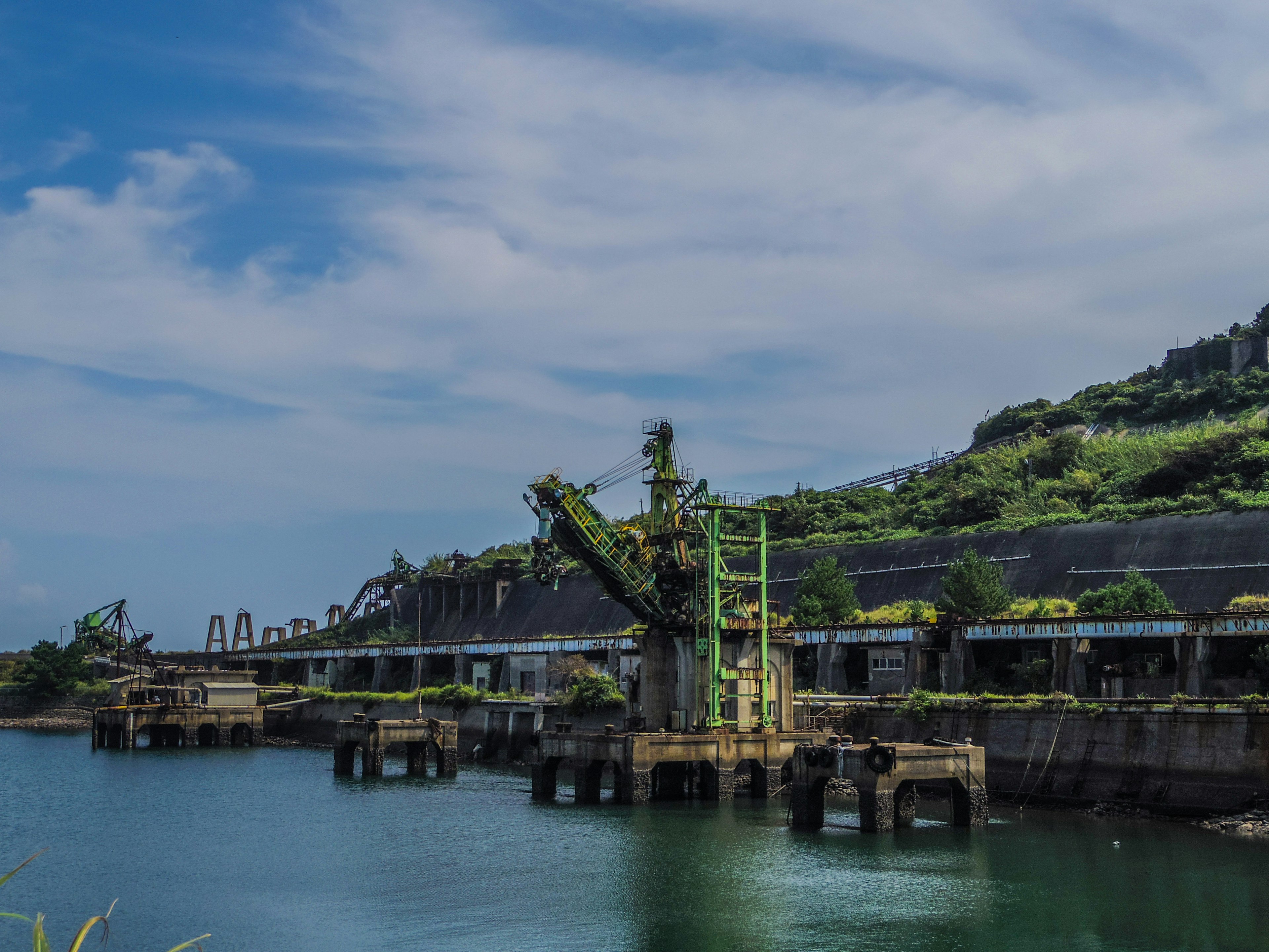 Escena de puerto abandonado con una grúa verde y agua tranquila