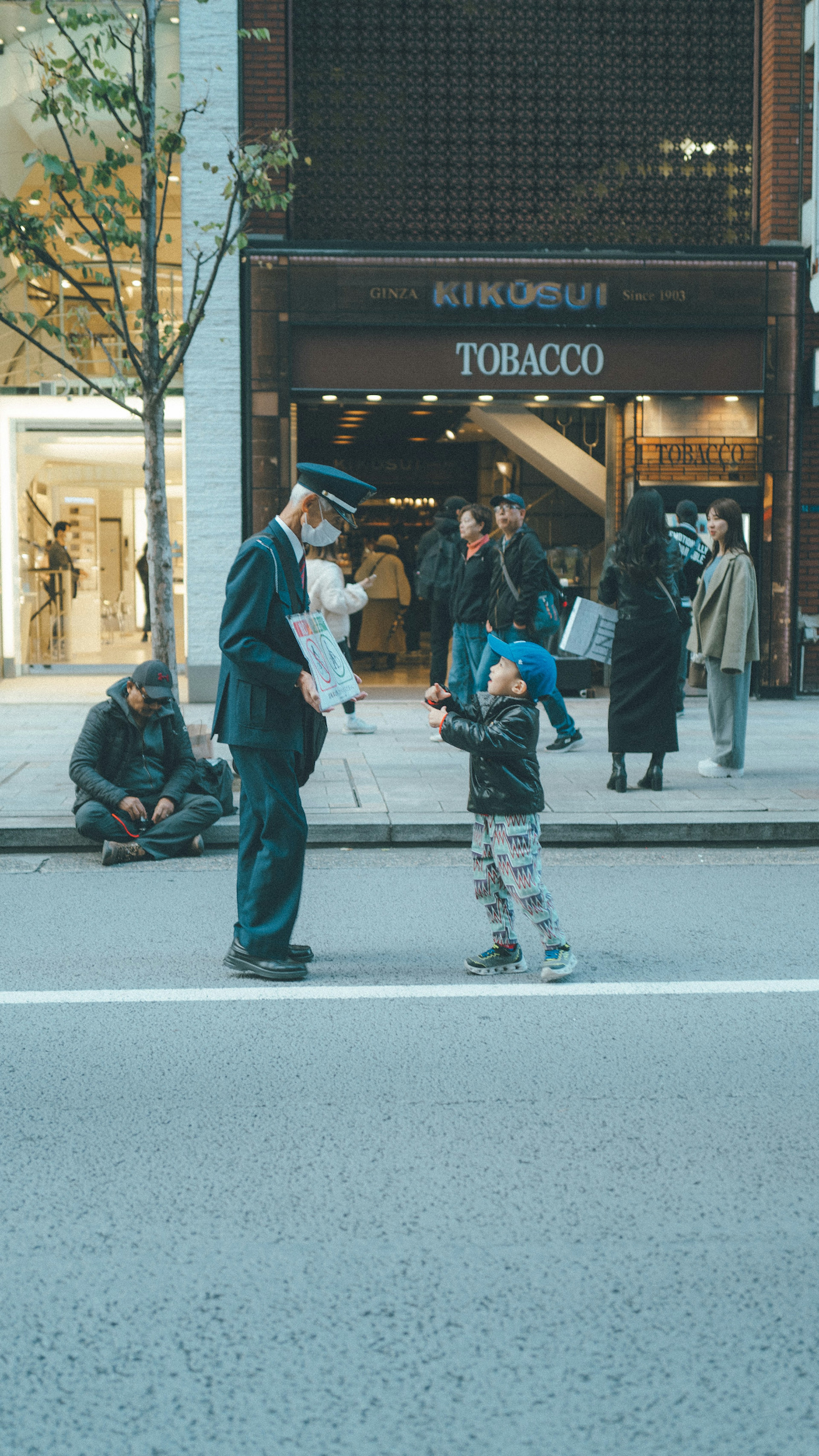 A child talking to a police officer in an urban setting with people in the background