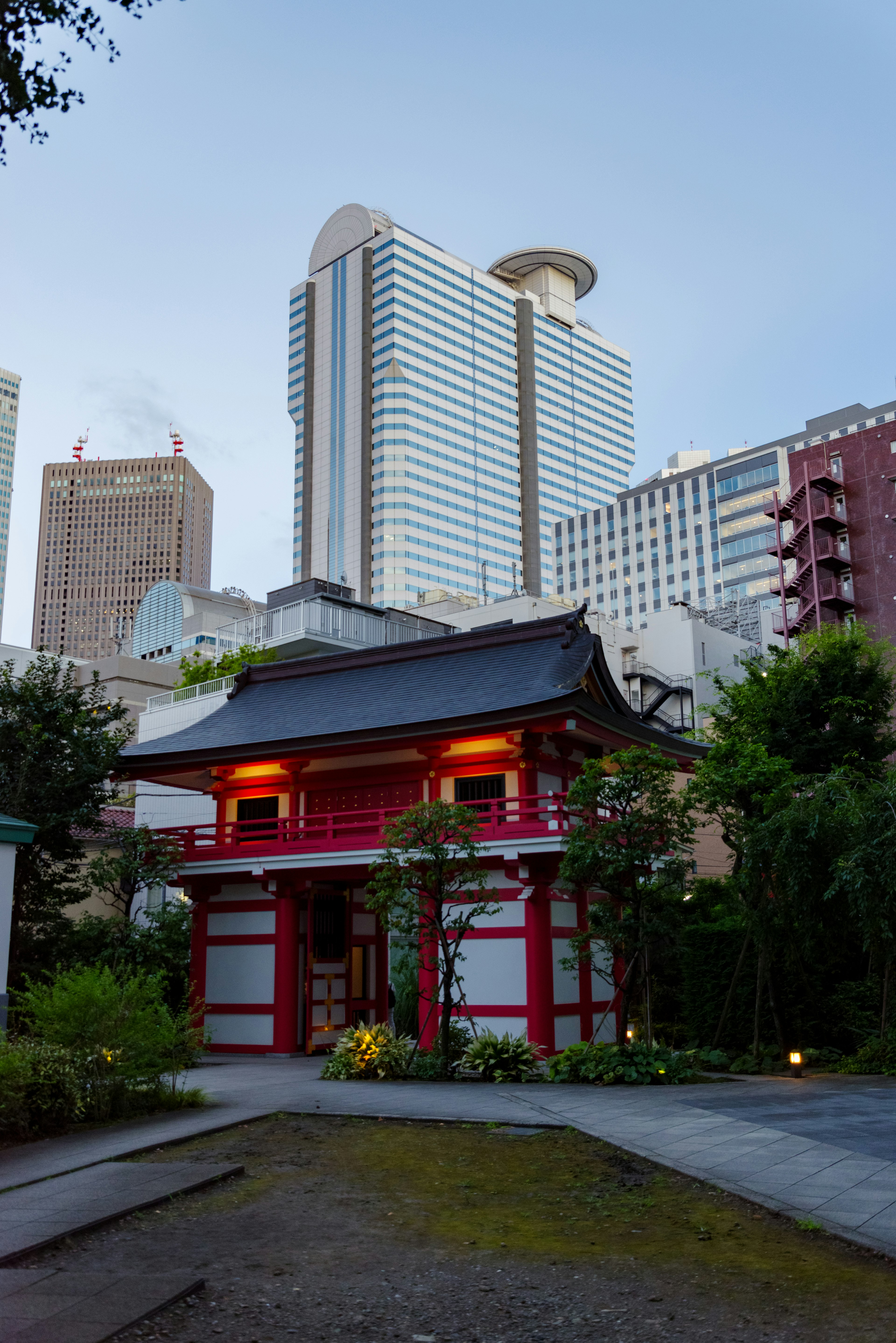 Traditional Japanese building contrasting with skyscrapers Red gate and green garden features