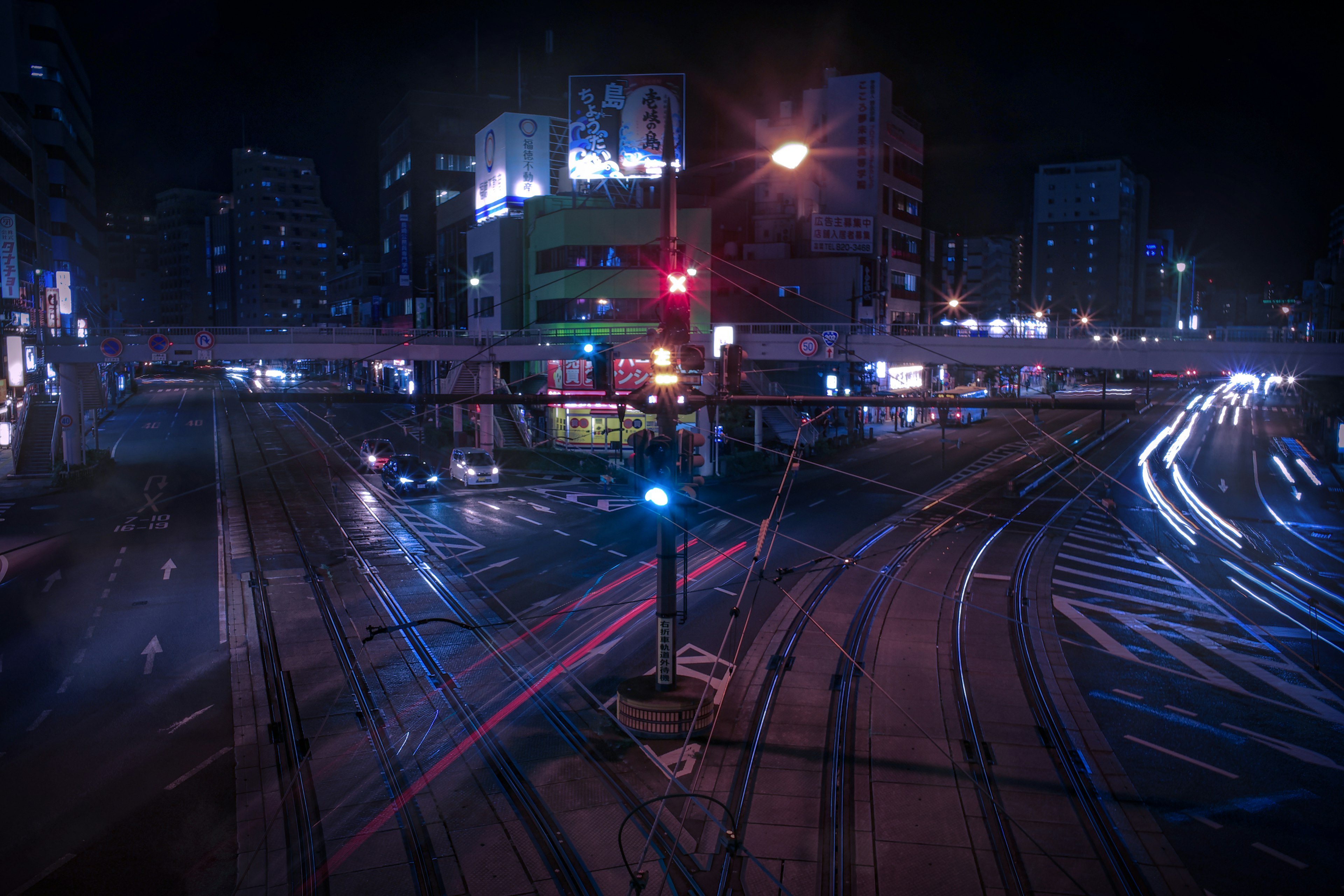 Paysage urbain nocturne avec des voies ferrées et un mouvement de véhicules présentant des feux de circulation rouges et bleus