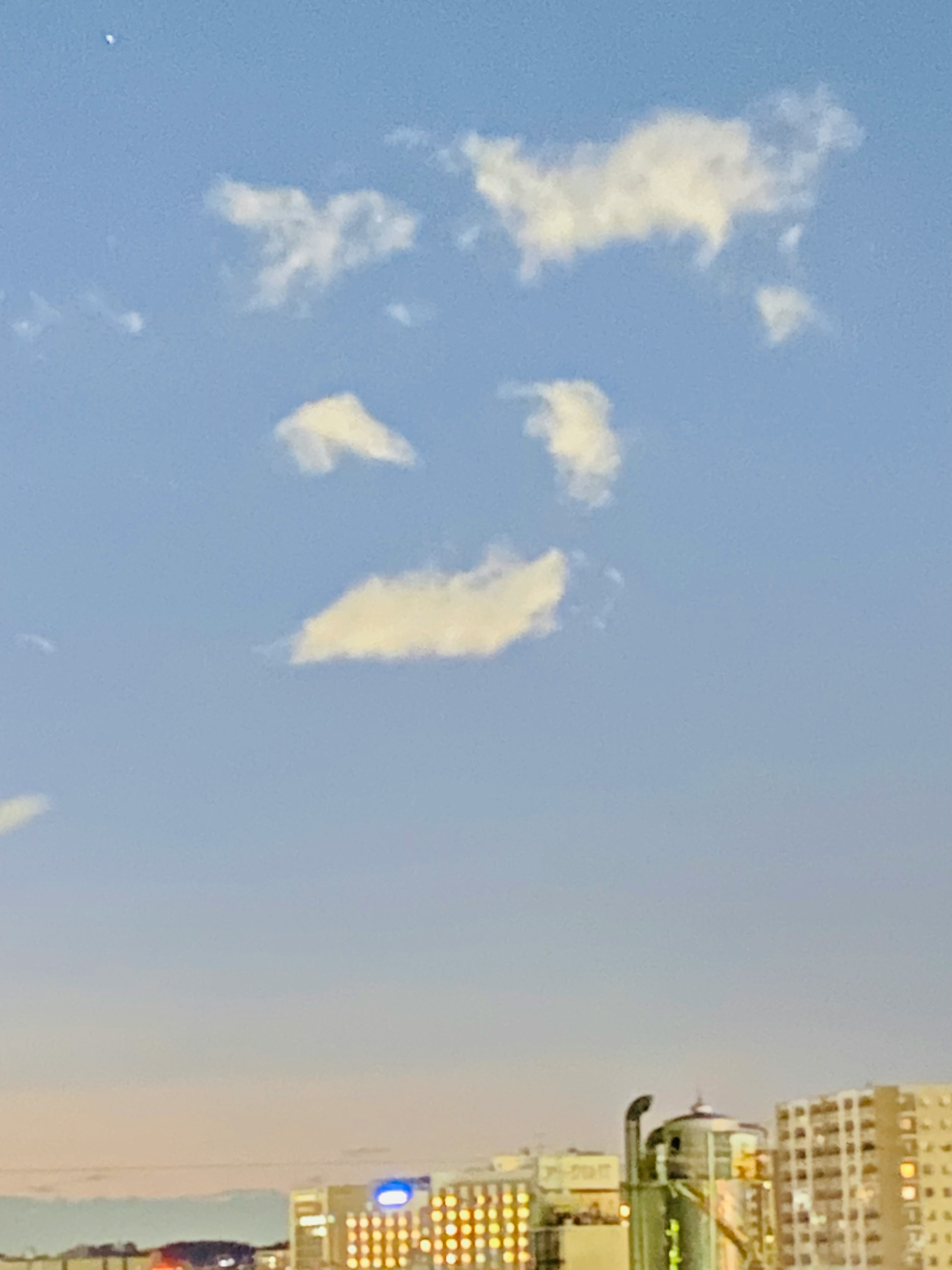 Una formación de nubes en forma de cara en un cielo azul sobre un horizonte urbano