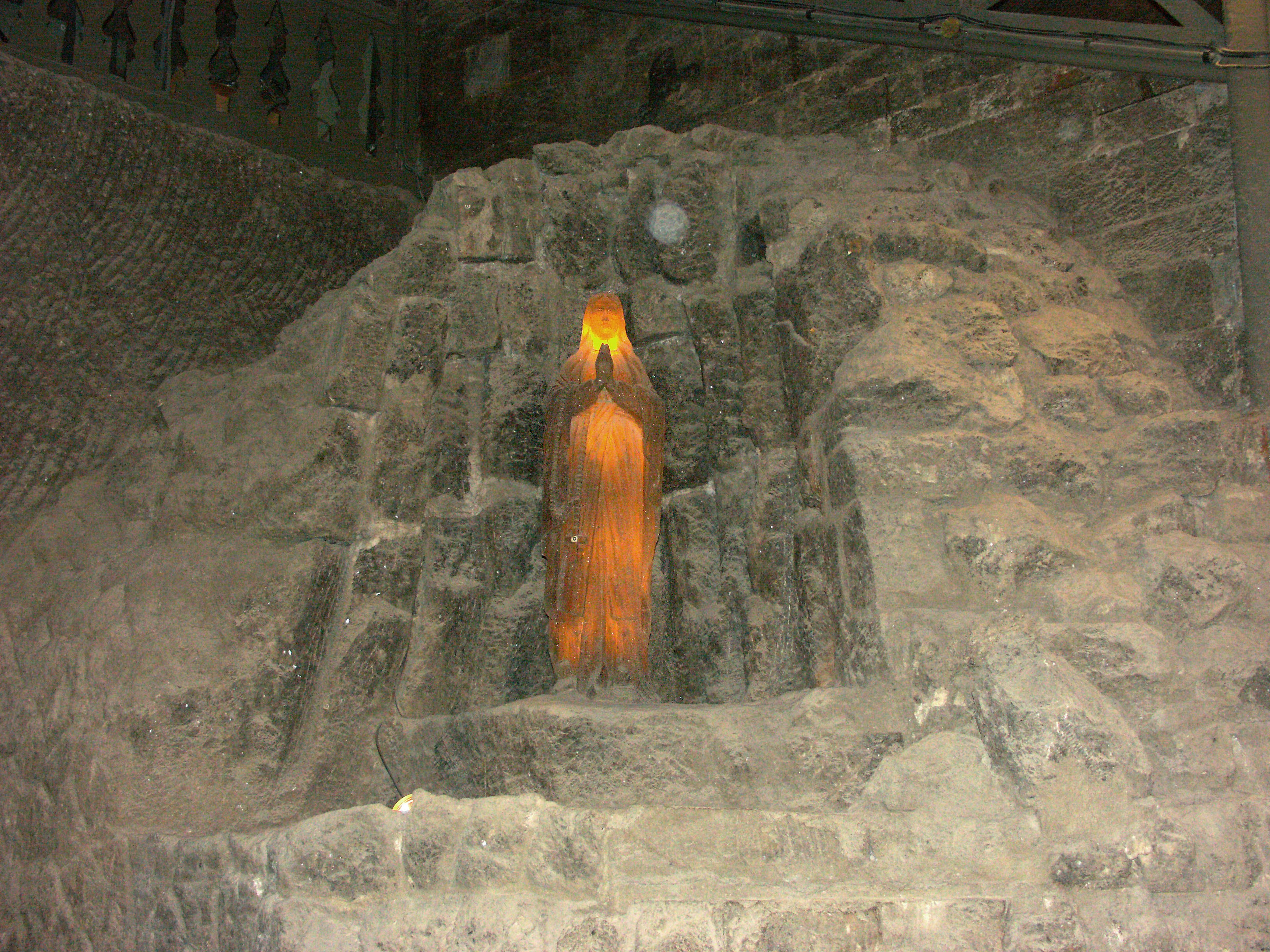 A statue emitting orange light embedded in a stone wall