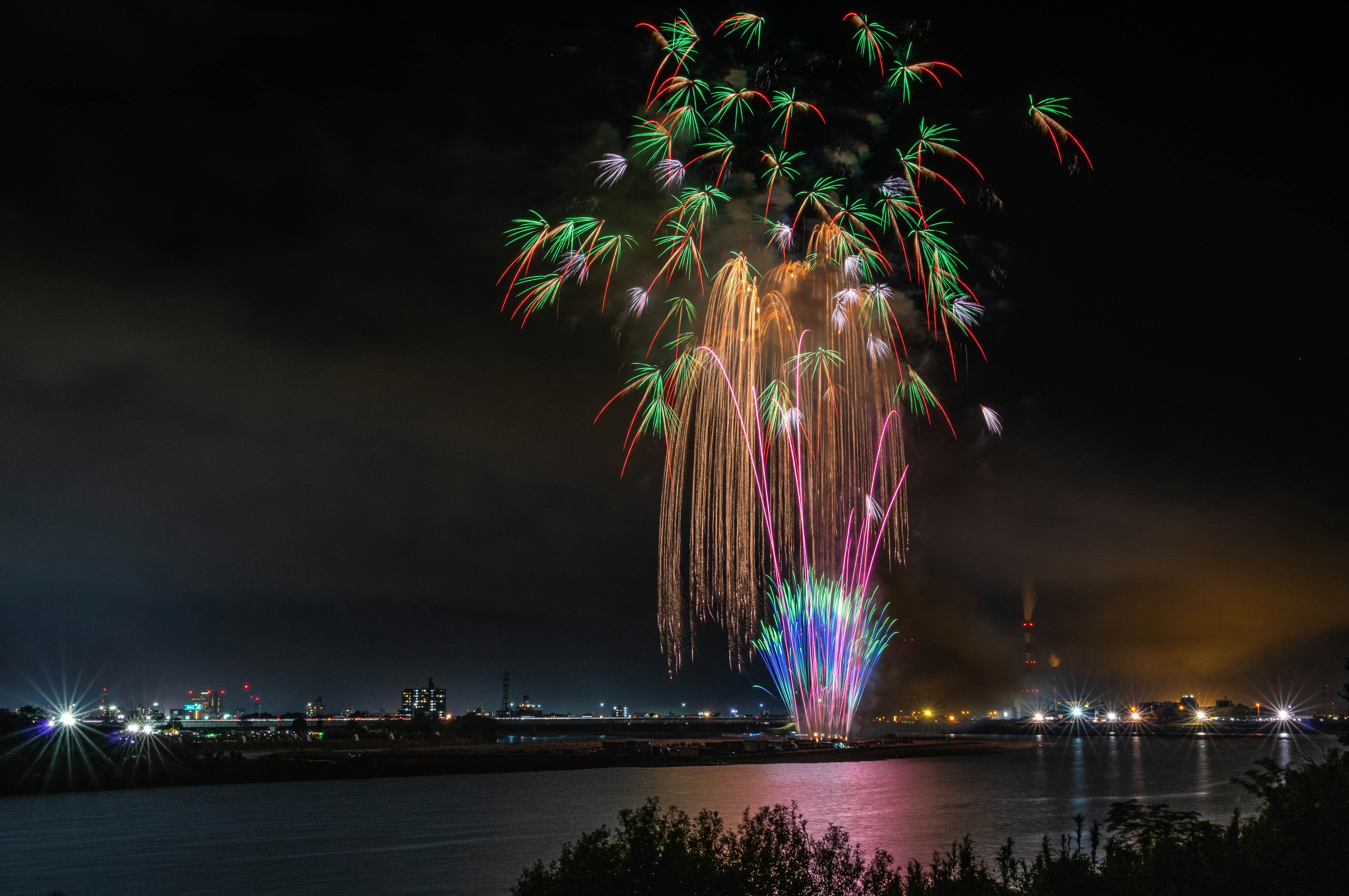 夜空に広がるカラフルな花火が水面に映る美しい景色