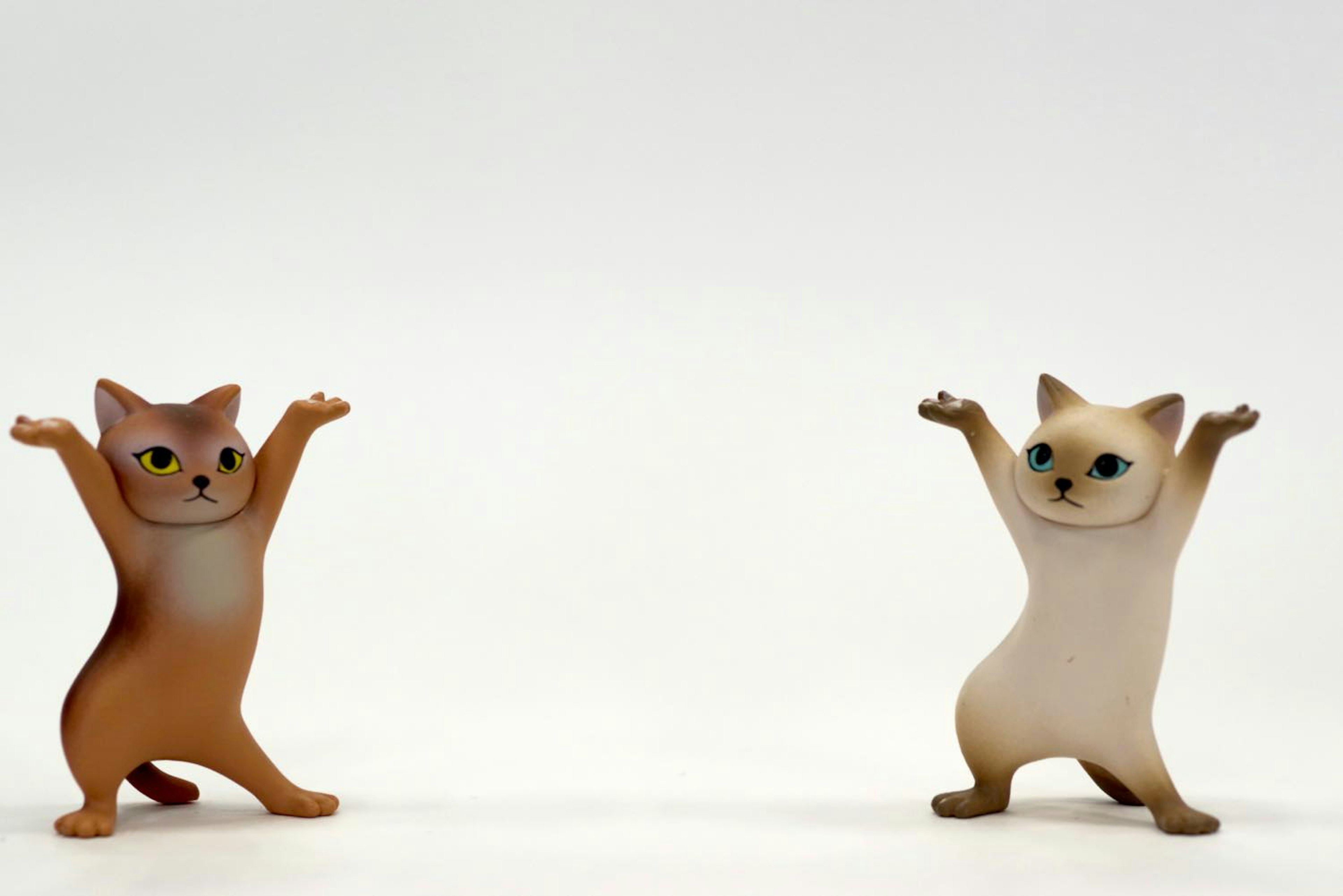 Two cat figurines raising their arms