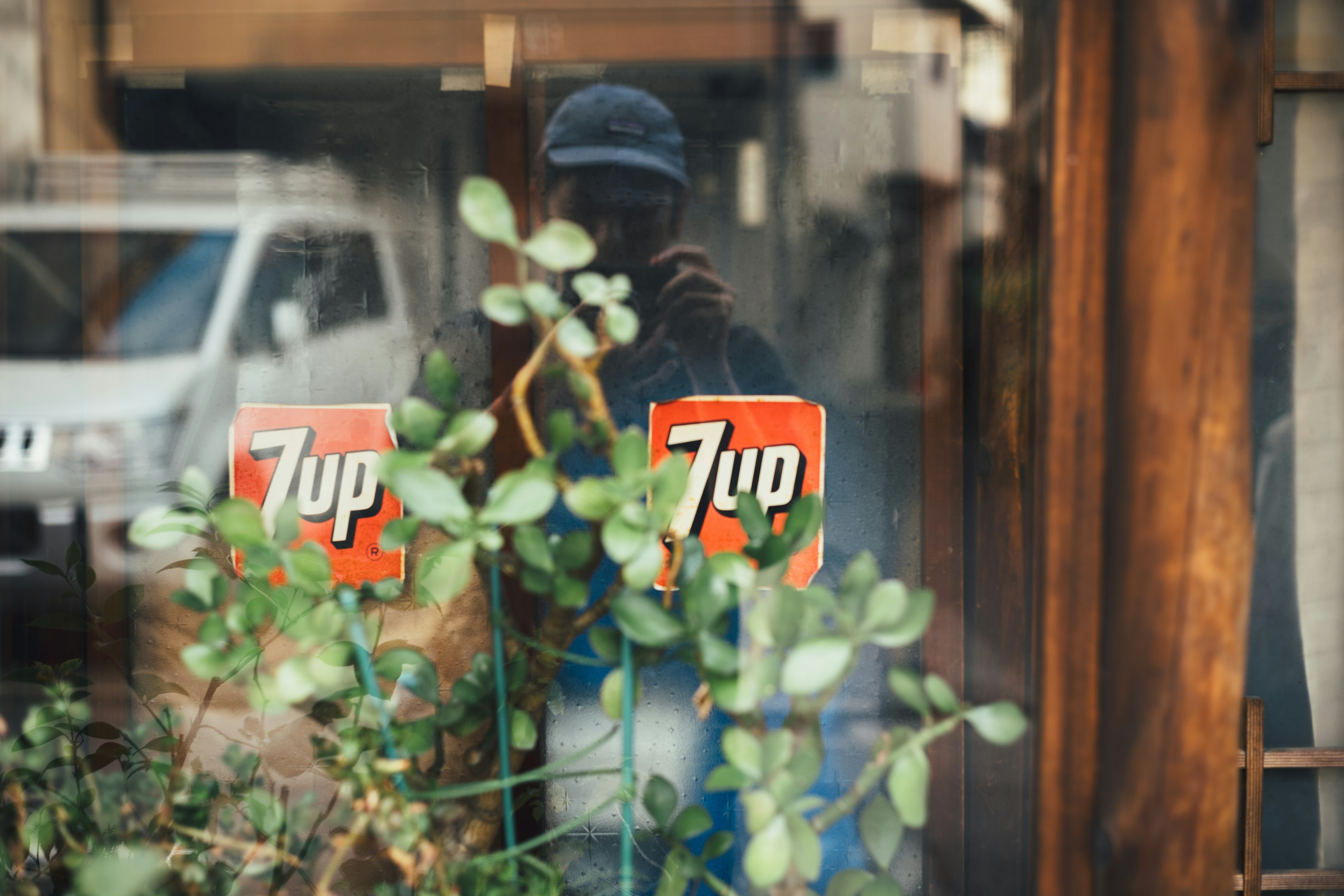 Fenêtre avec des logos 7up, des plantes et le reflet d'une personne