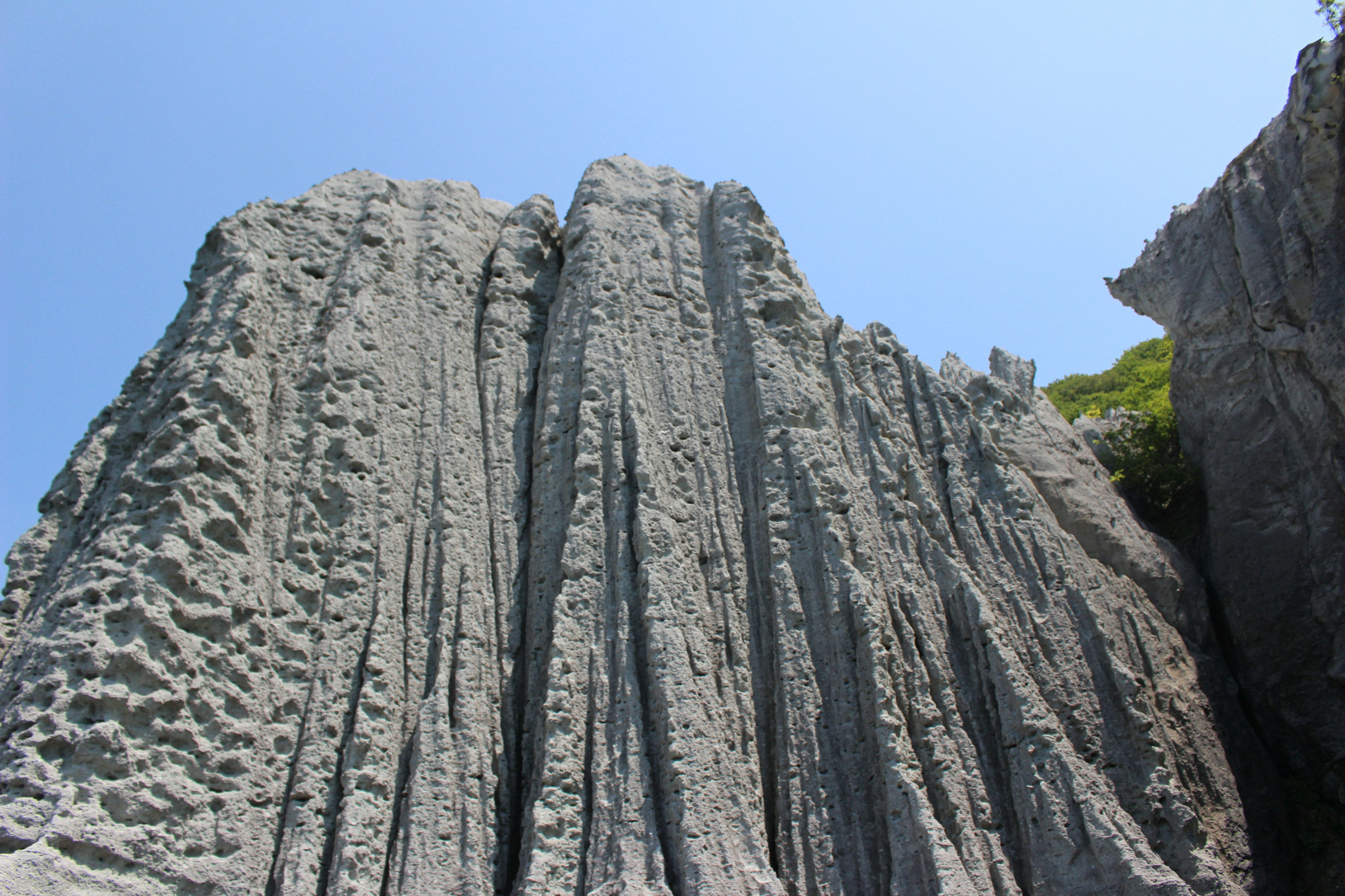 Formazioni rocciose verticali sulla costa sotto un cielo blu chiaro