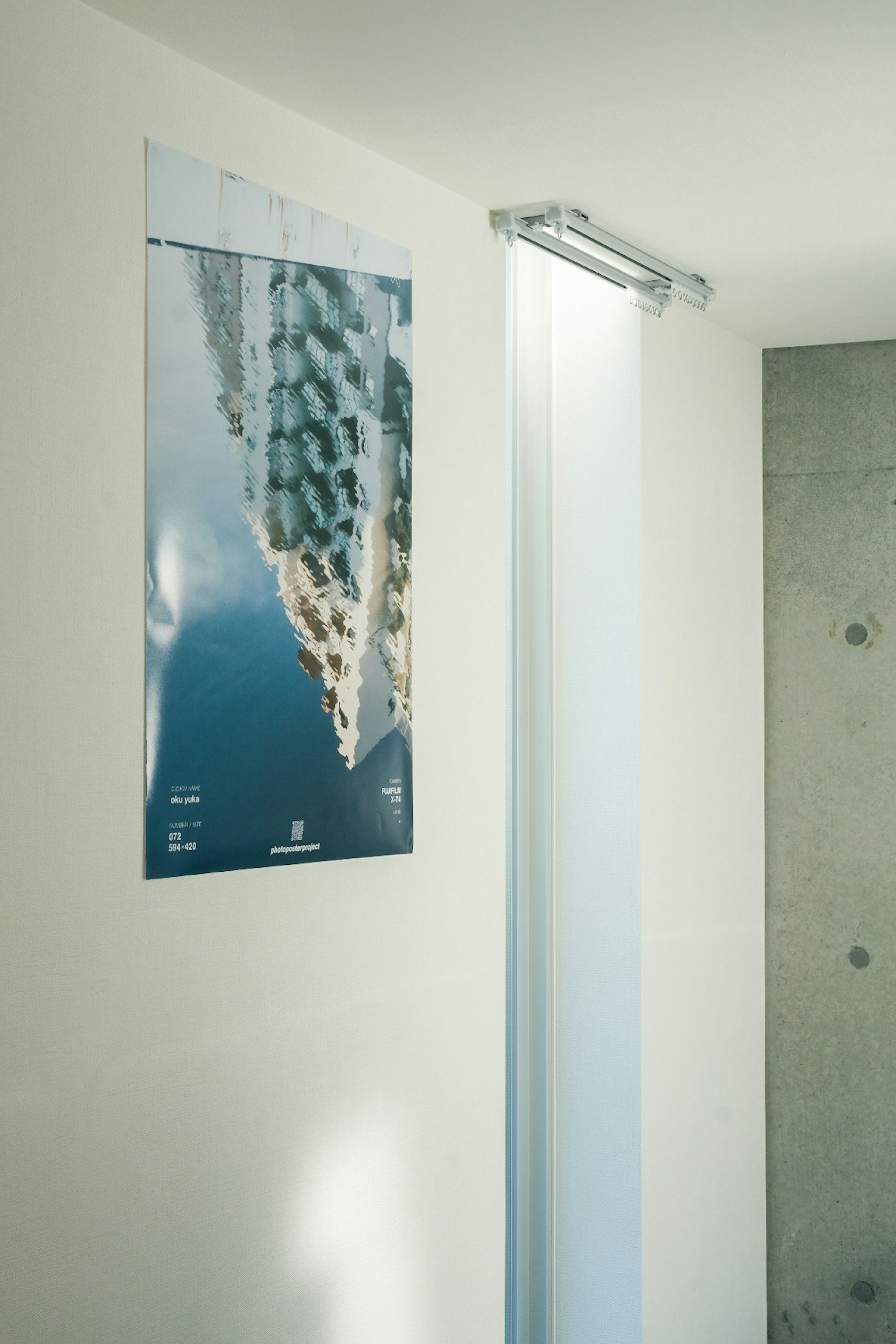 Modern poster hanging on a white wall with a curtain and concrete feature