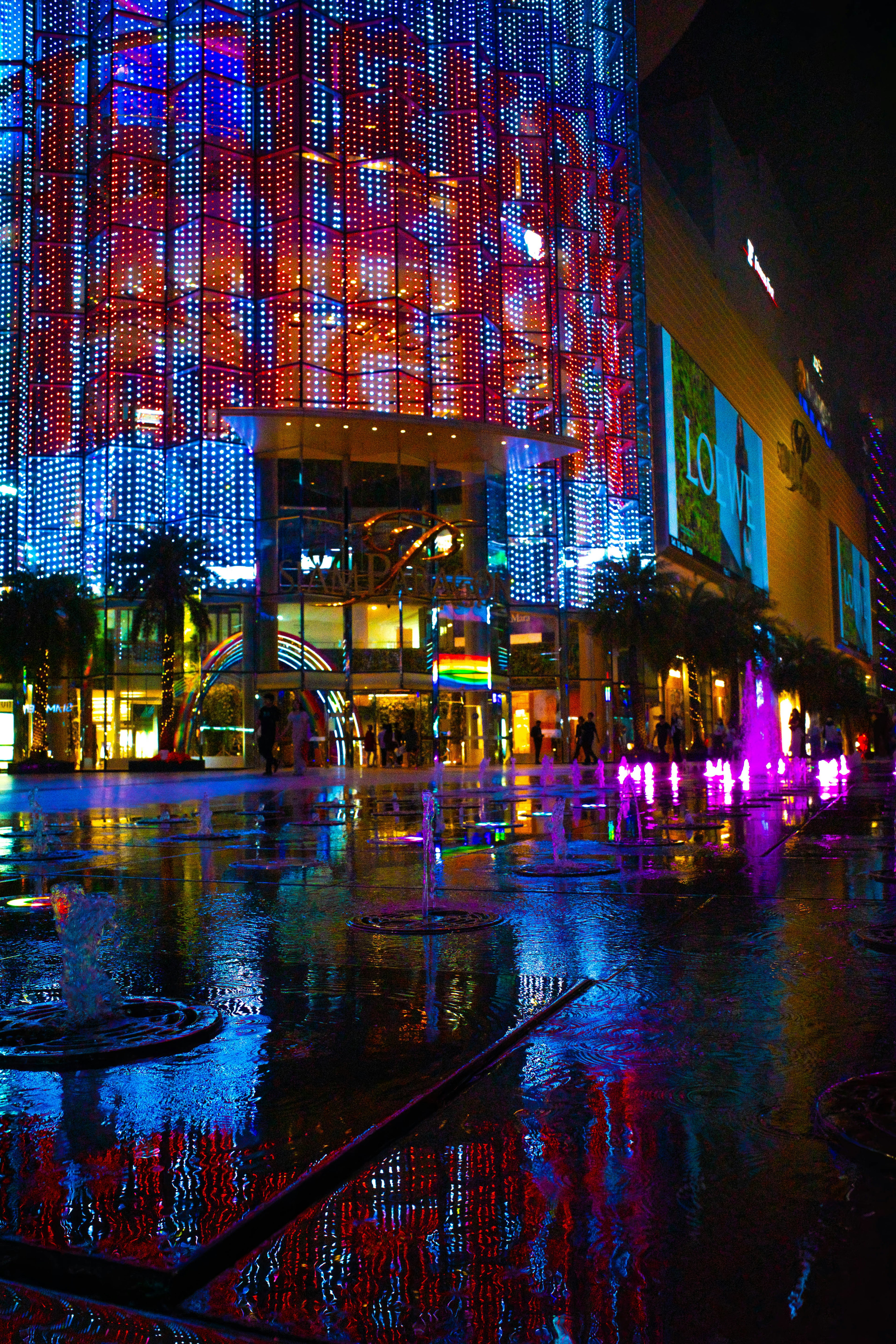 Luci al neon colorate che si riflettono su un edificio urbano bagnato di notte