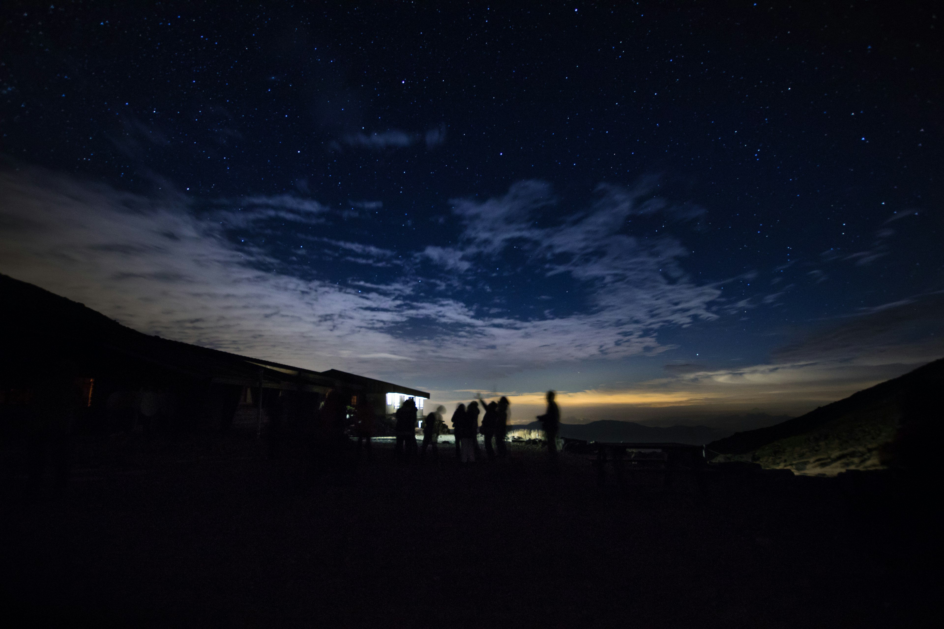 夜空に星が輝く中でシルエットの人々が集まっている風景