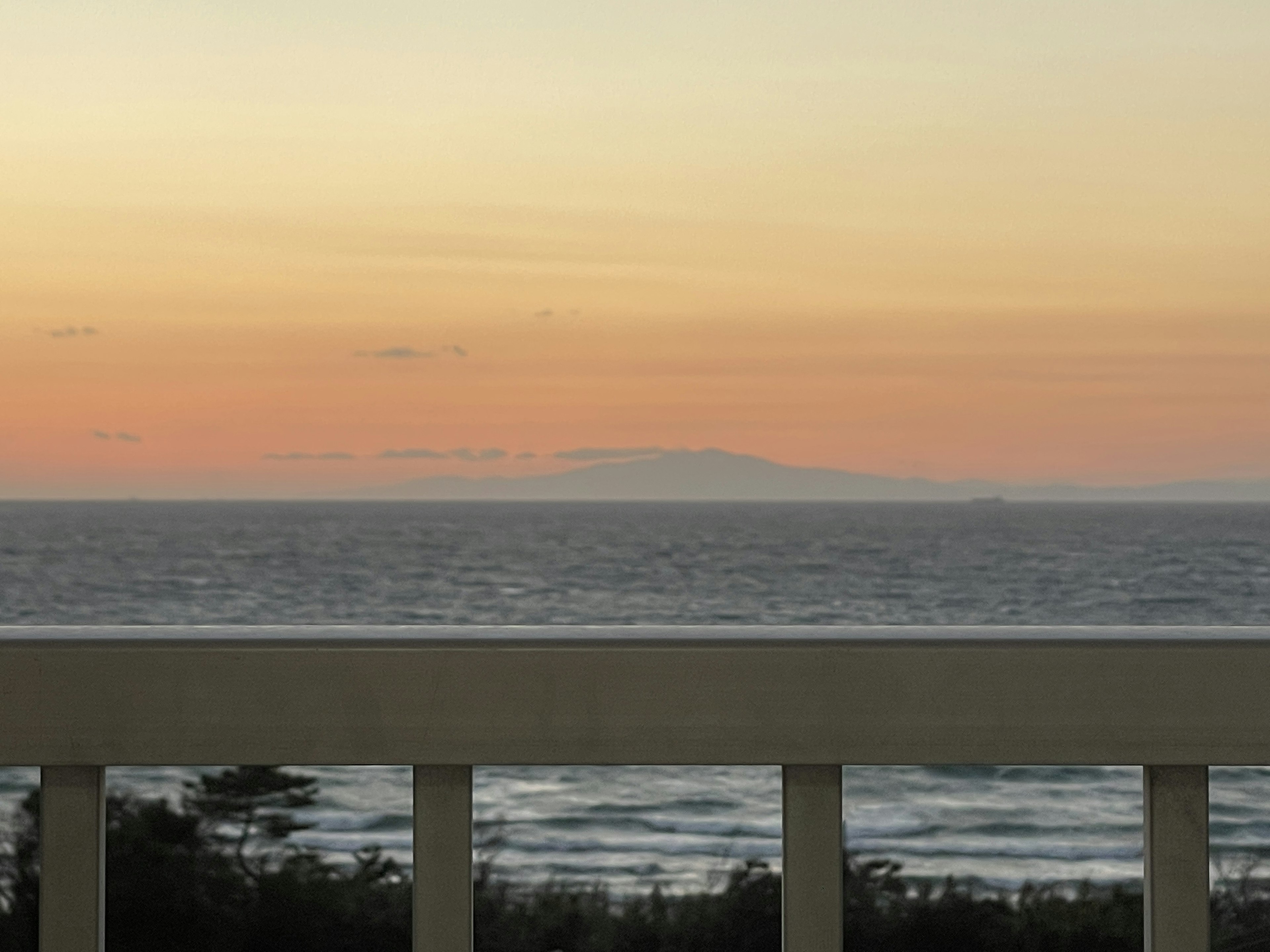 Vista dal balcone sull'oceano al tramonto con un'isola distante