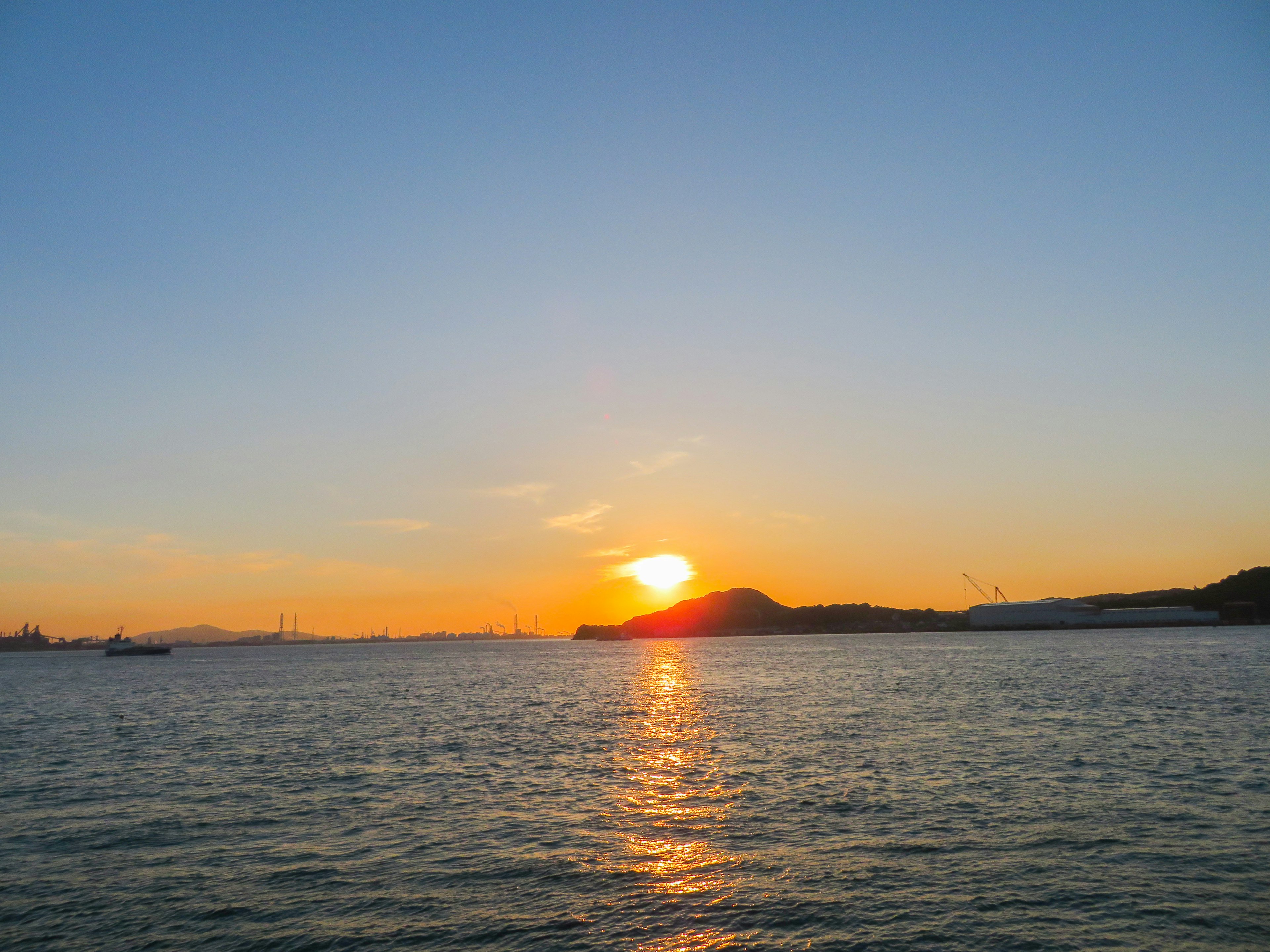 Beautiful sunset over the ocean with a silhouette of a hill