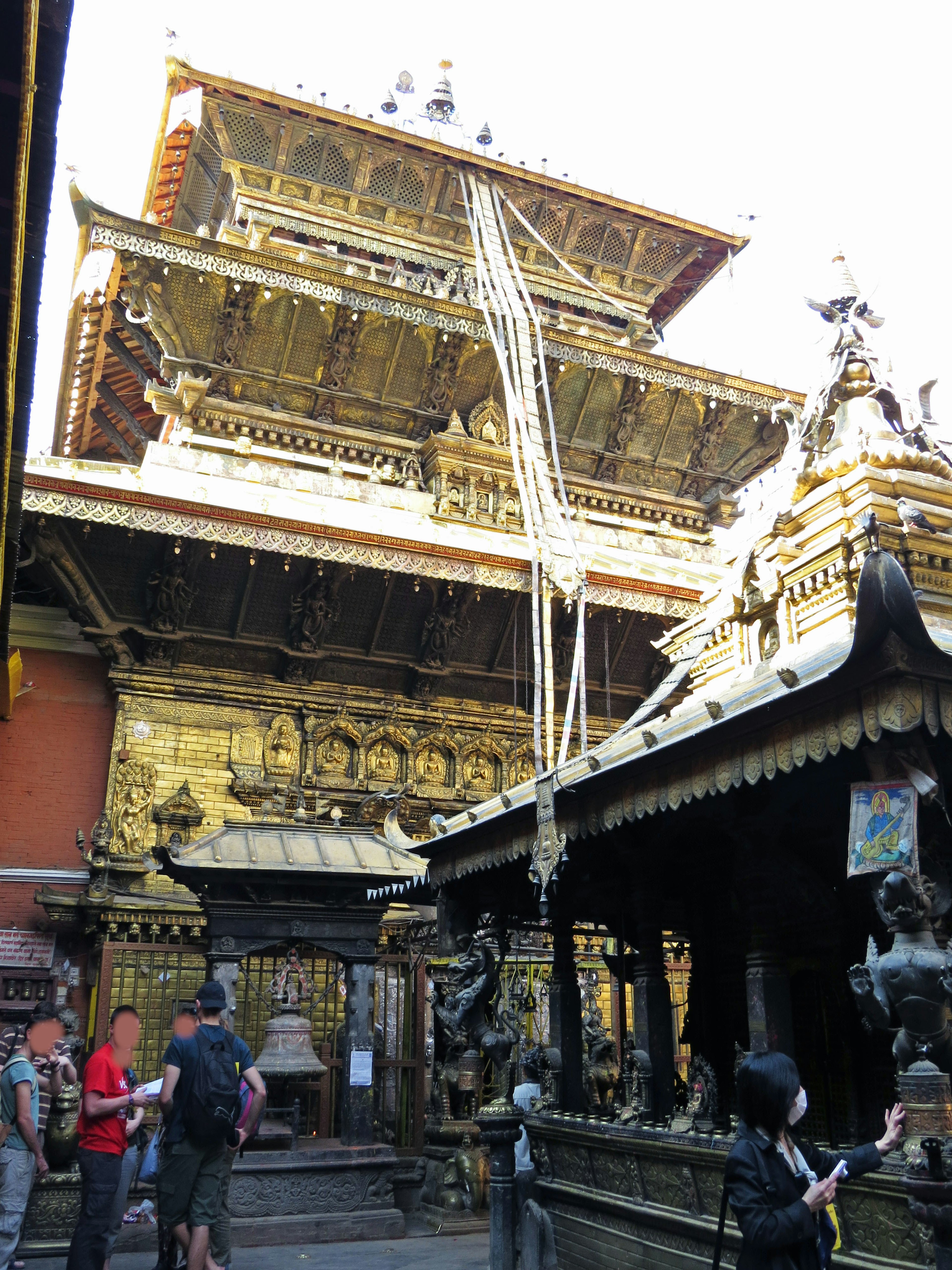 寺院の金色の装飾と人々の姿が特徴的な風景