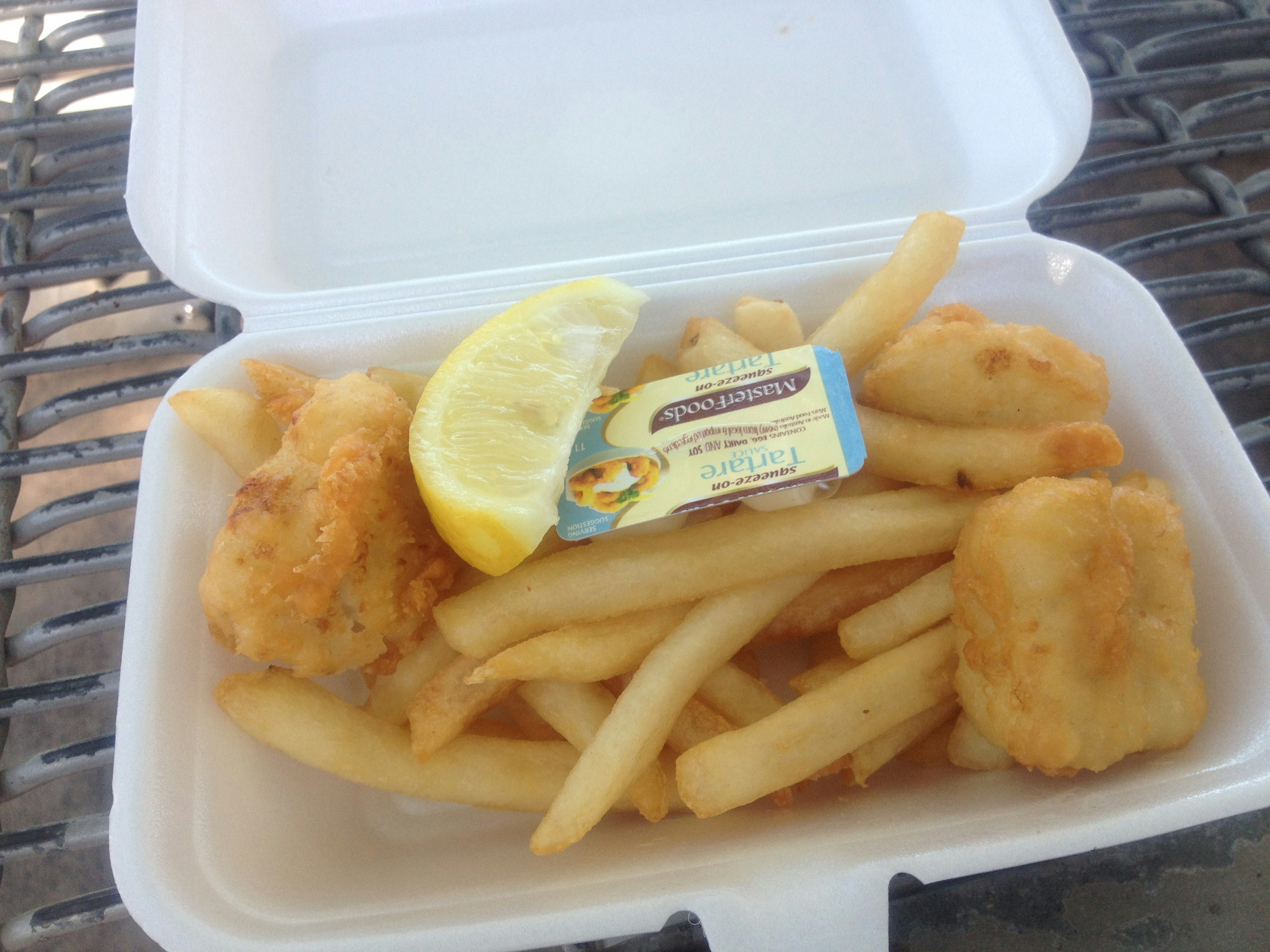 Fried fish and french fries served with a lemon wedge and dipping sauce