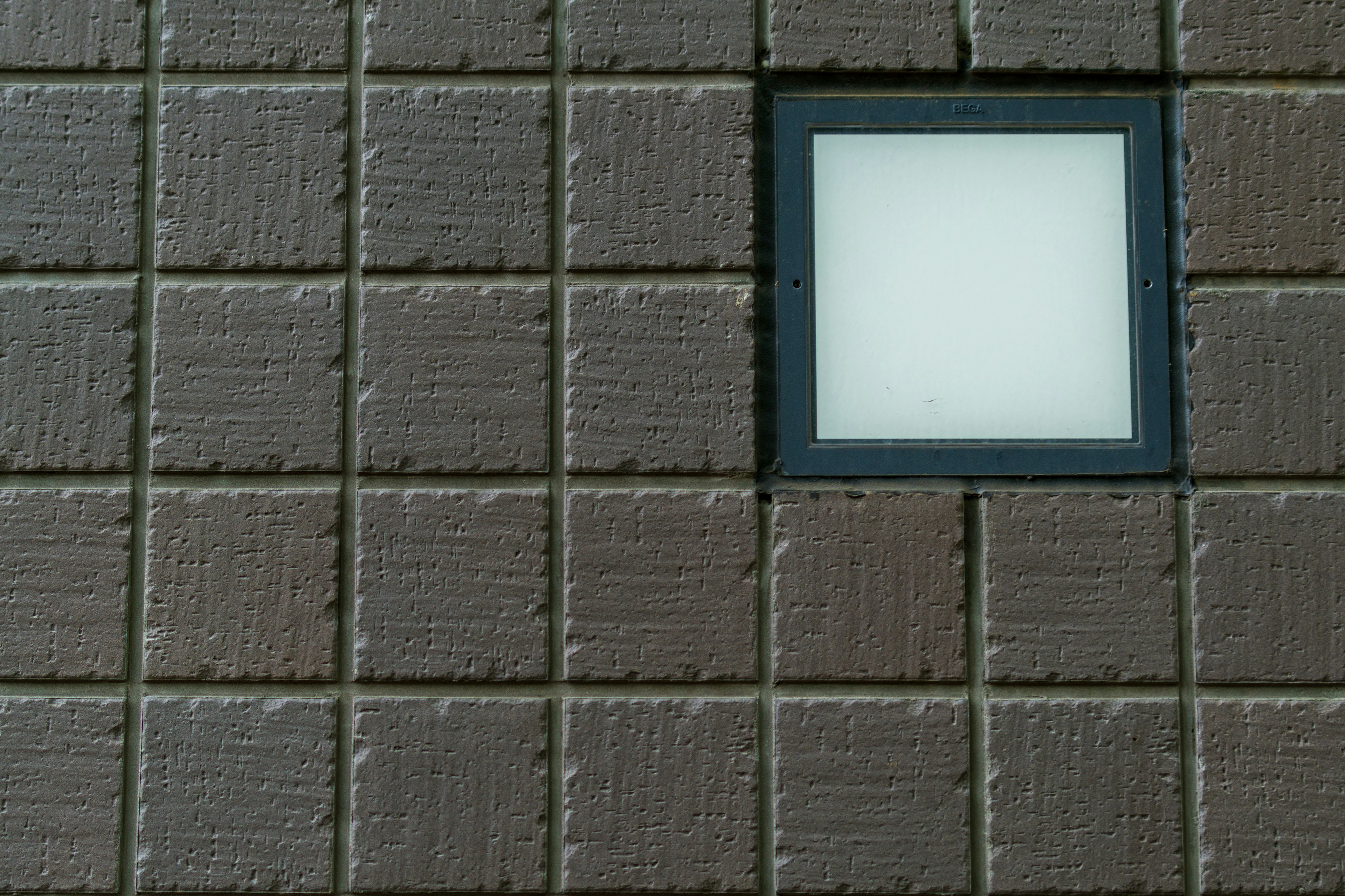 Square white light fixture on textured brown wall