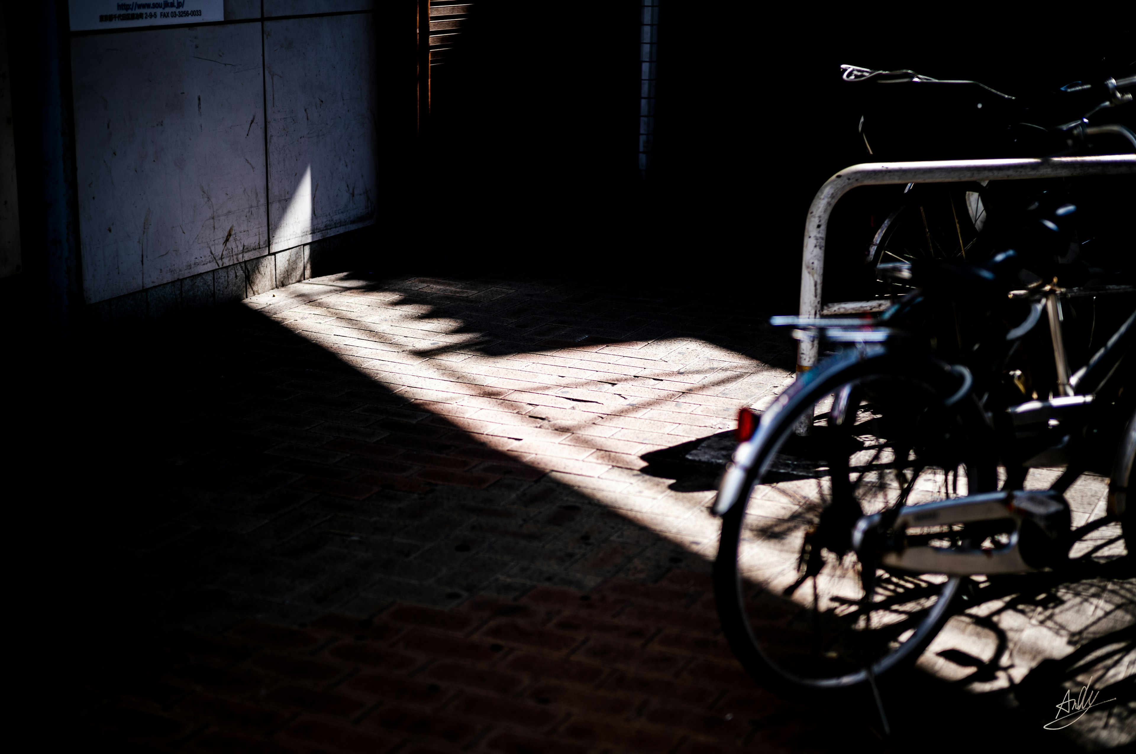 自転車が置かれた暗い通路の影と光のコントラスト